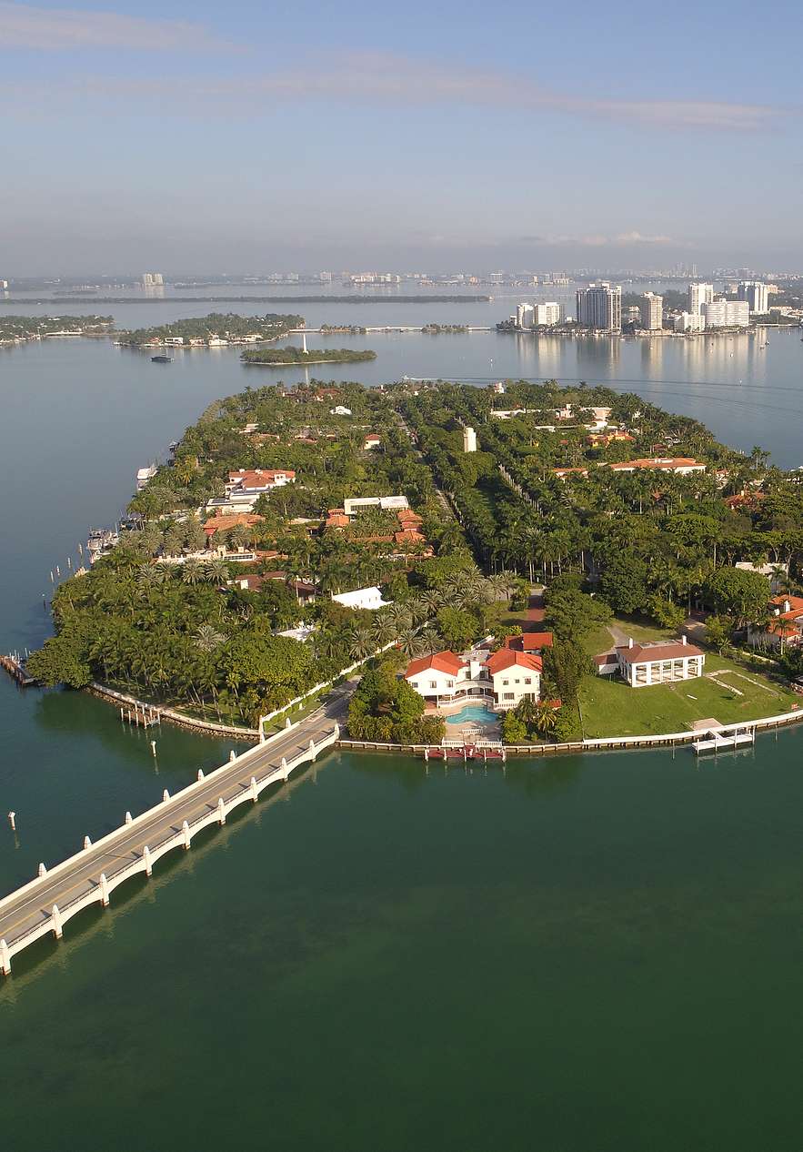 Vista aérea de Star Island en Miami, con casas lujosas y vegetación intensa, conectada a la ciudad por un puente