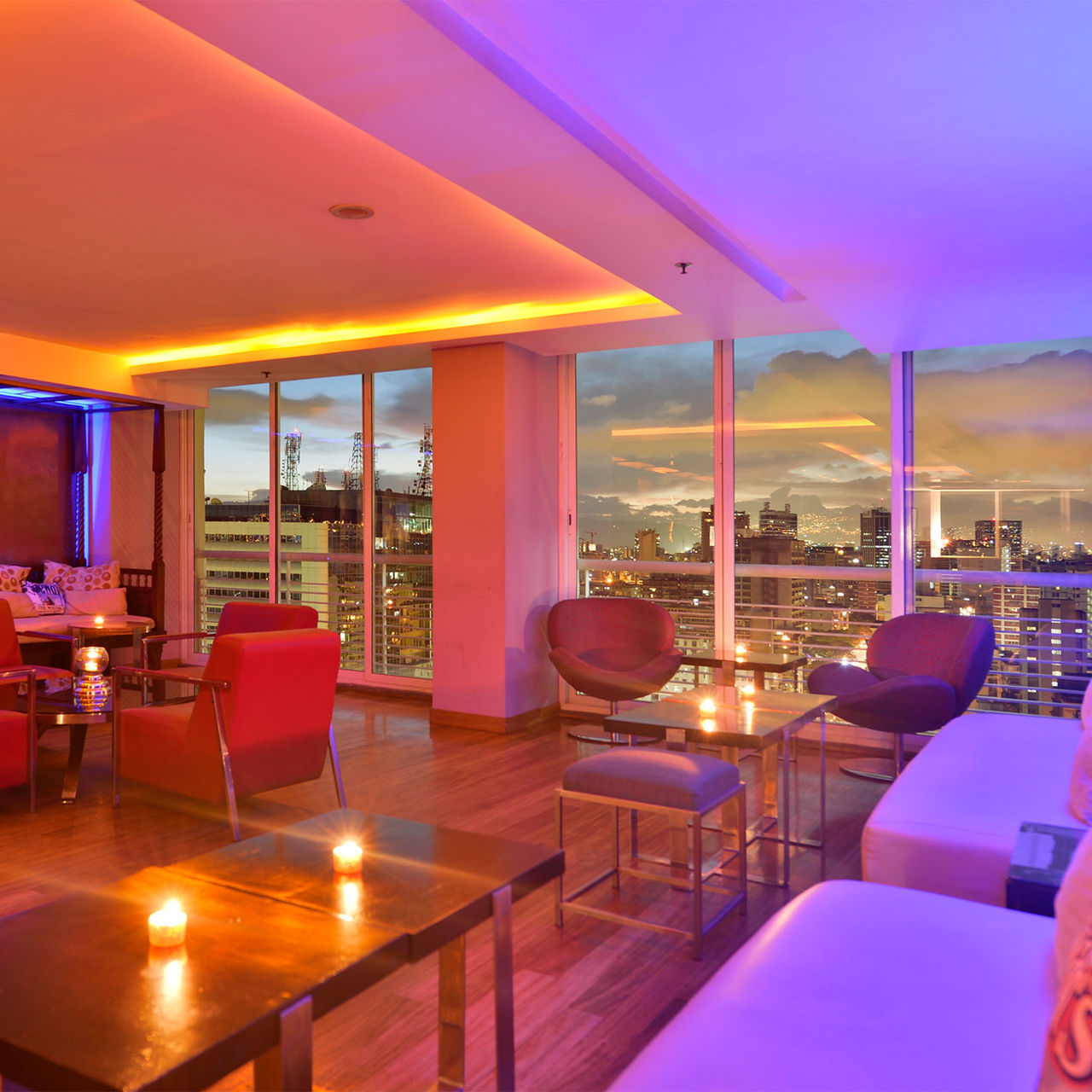 Bar del Pestana Caracas con vista panorámica de la ciudad al atardecer, un espacio moderno con sofás y sillones