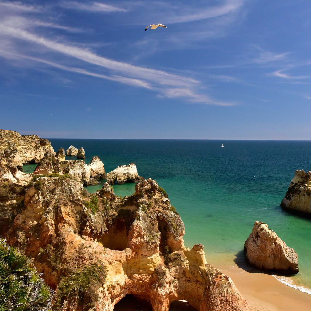 Vista de la Playa de los 3 Hermanos, con las rocas, vegetación, arena, el mar a un lado y el cielo con pocas nubes