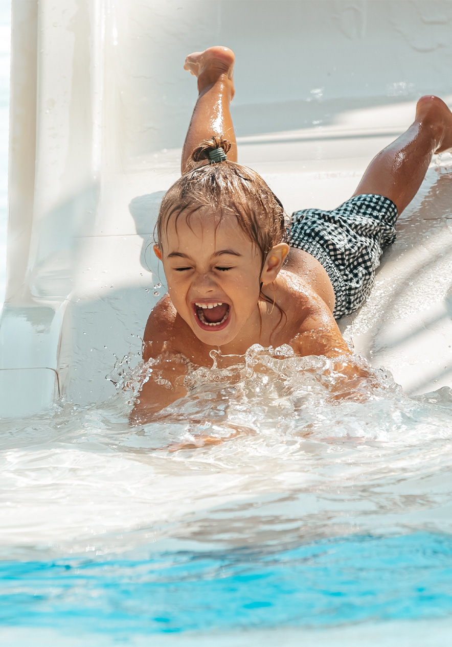 Niña se desliza sonriente por un tobogán de agua en Slide & Splash, Algarve