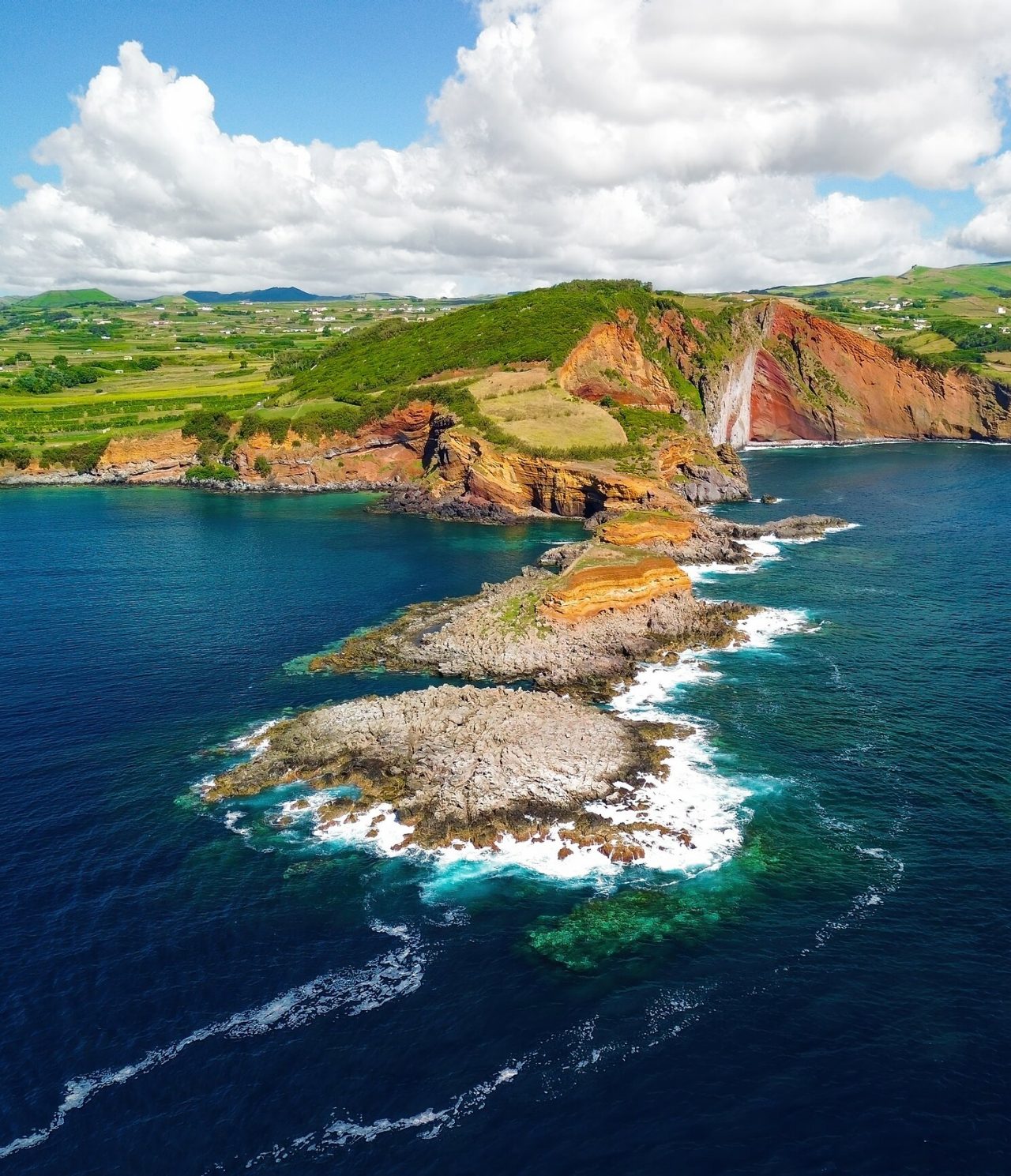 Vista aérea de formaciones rocosas volcánicas esculpidas por el mar, rodeadas por el océano y vegetación verde