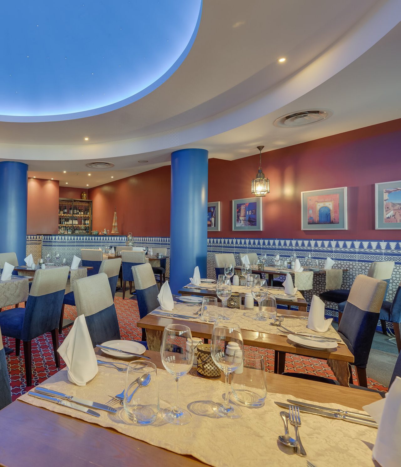 El restaurante Au Tagine, del Hotel 5 Estrellas en Funchal, Madeira, tiene un salón amplio con cuadros y mesas con sillas