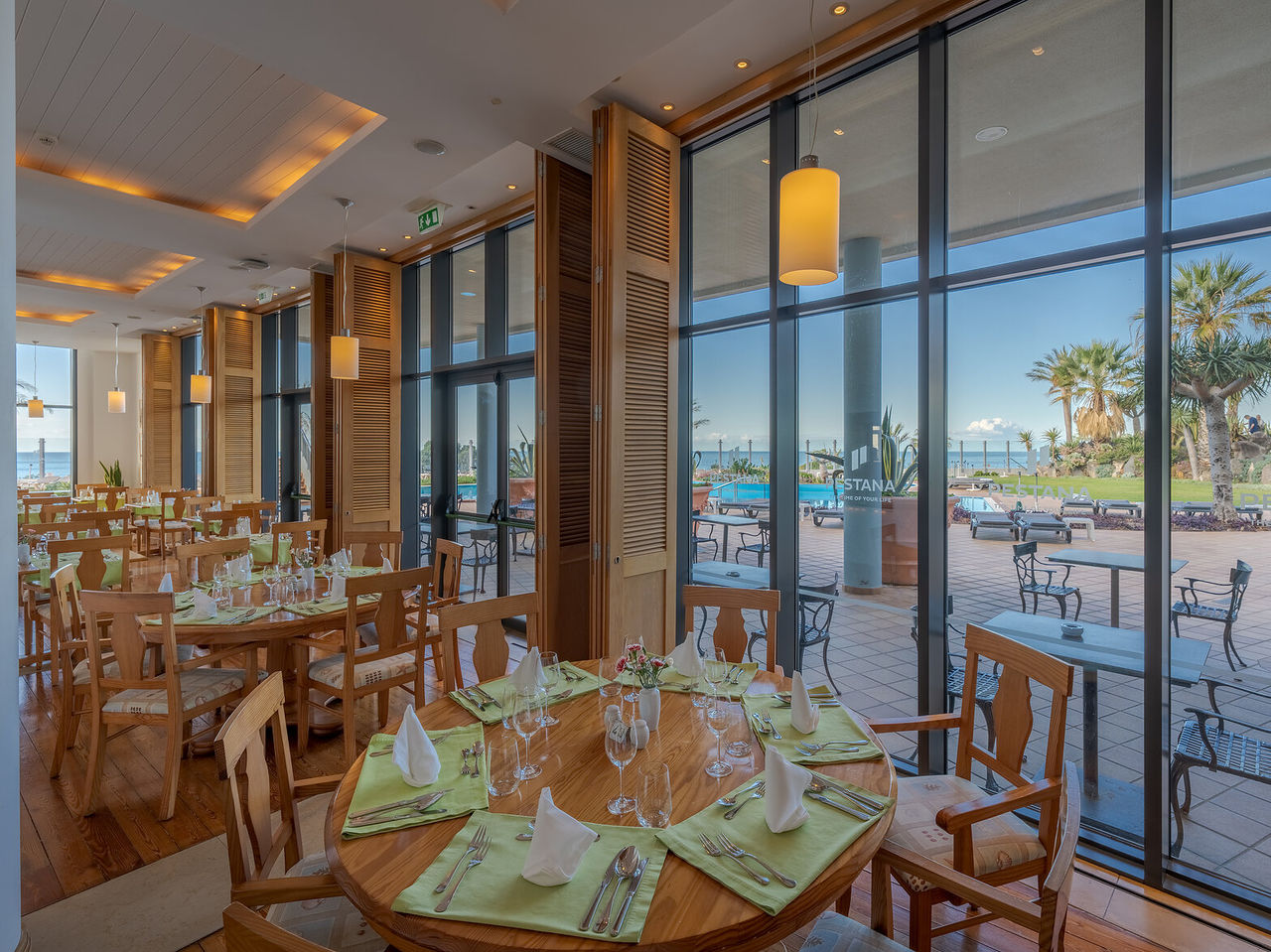 El restaurante Cabo Girão, del Hotel 5 Estrellas en Funchal, Madeira, tiene un salón con mesas, cubiertos y vista al mar