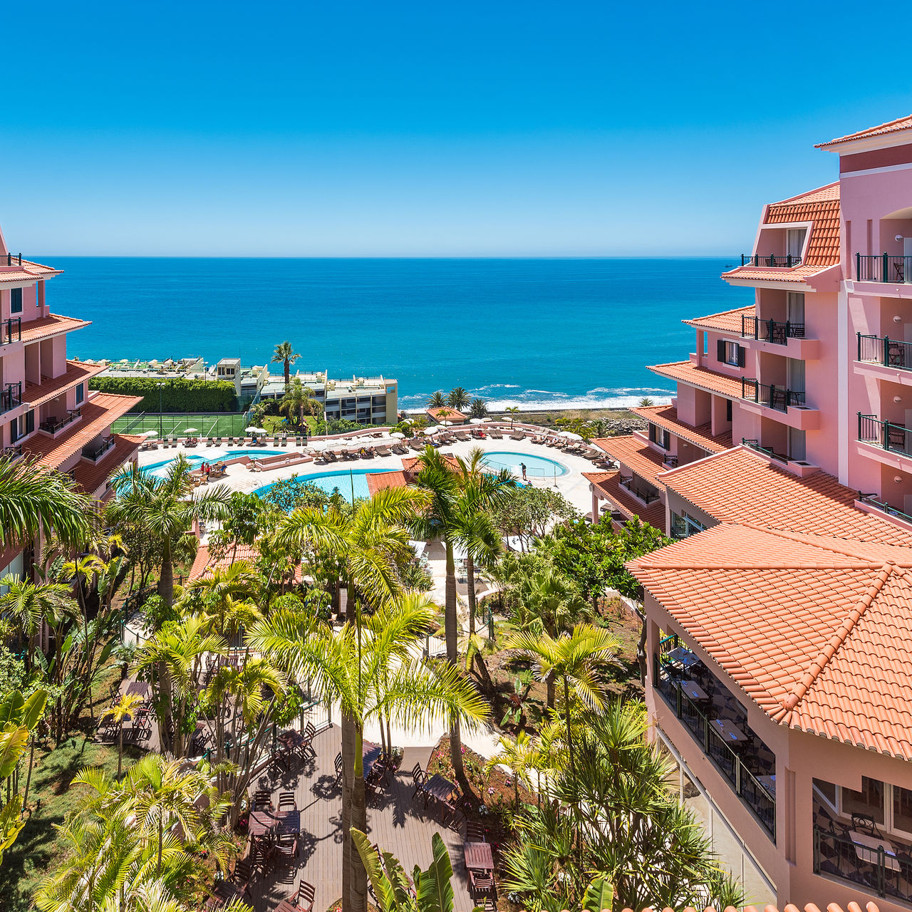 Vista panorámica del Pestana Royal All Inclusive, con la piscina exterior y el campo de tenis en el centro, y el mar al fondo