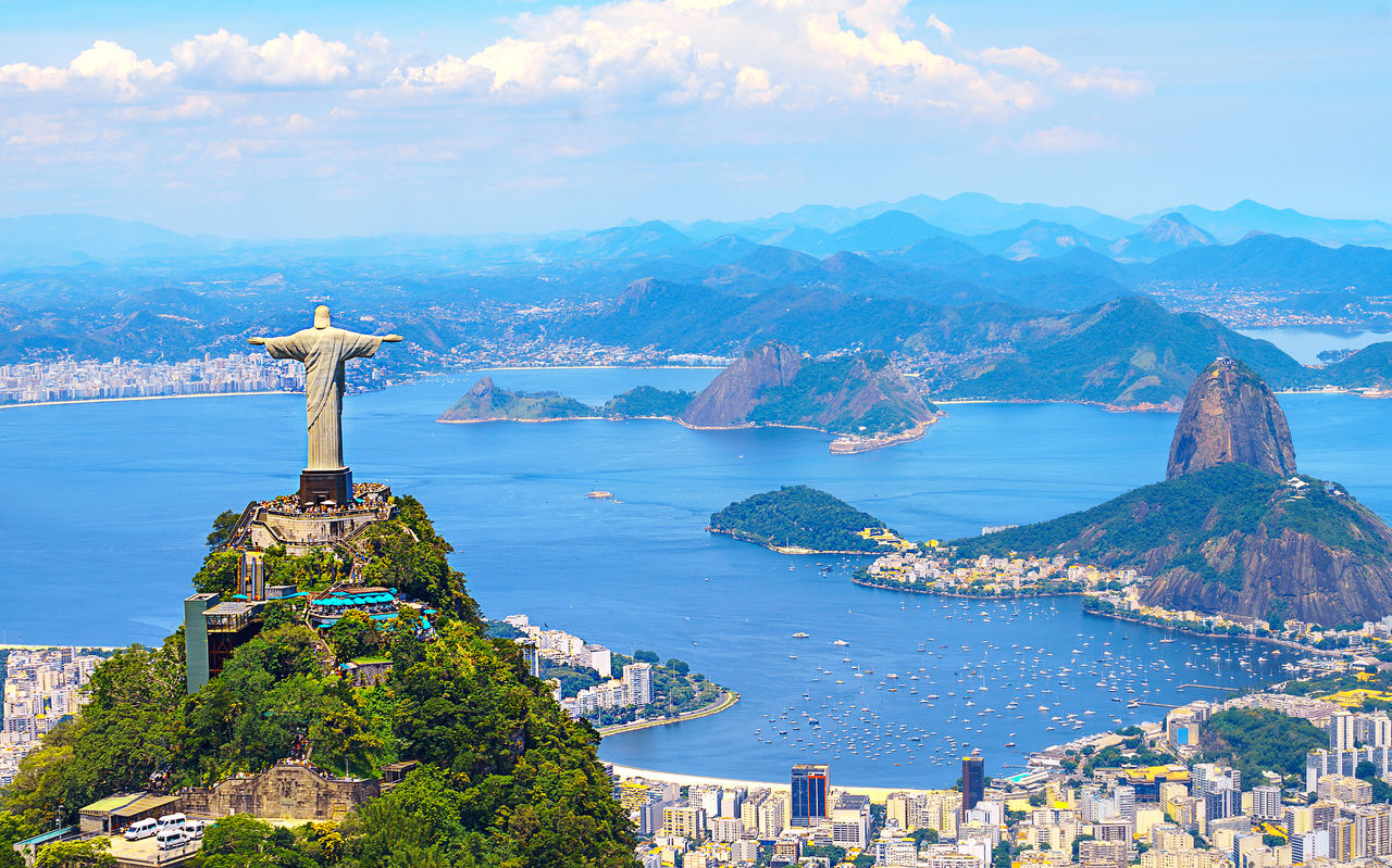 Icônica estátua do Cristo Redentor no Rio de Janeiro, com a cidade, o oceano e a praia de fundo