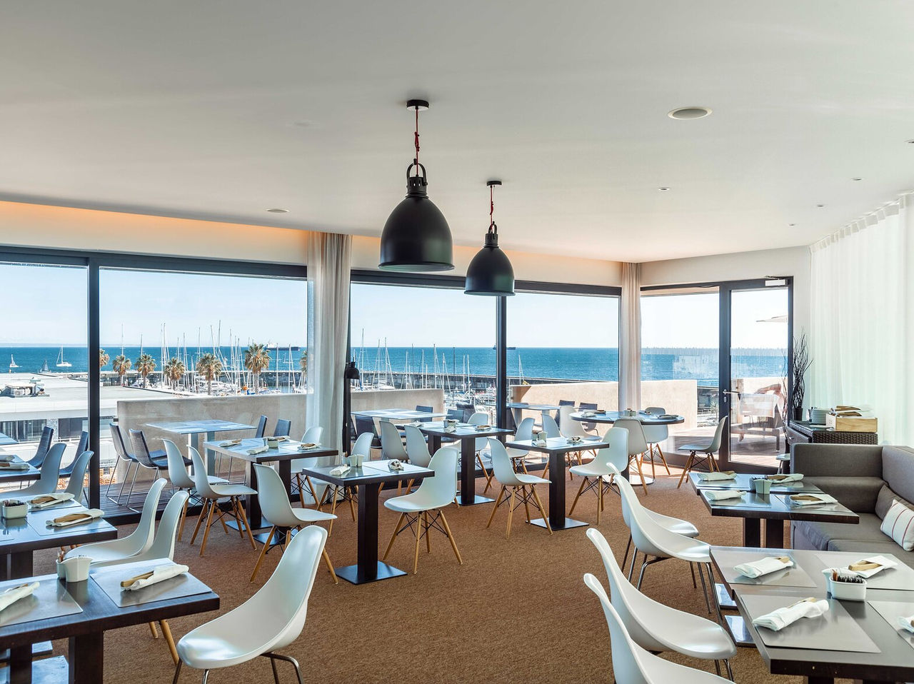 O restaurante Maris Stella, do Hotel 5 Estrelas em Cascais tem várias mesas e cadeiras e vista para a marina de Cascais