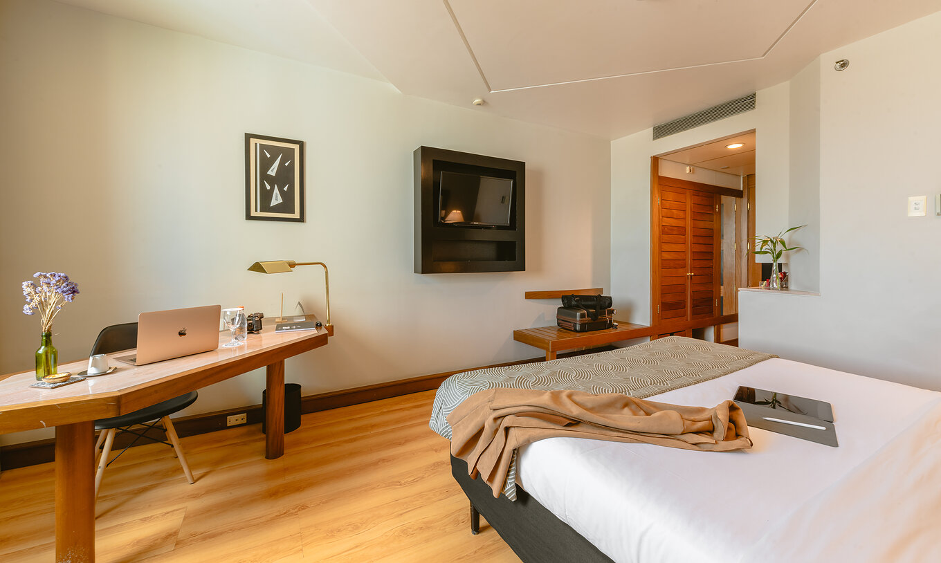 The Queen Standard of Pestana São Paulo has a corridor at the entrance, a television at the foot of the bed, and a desk