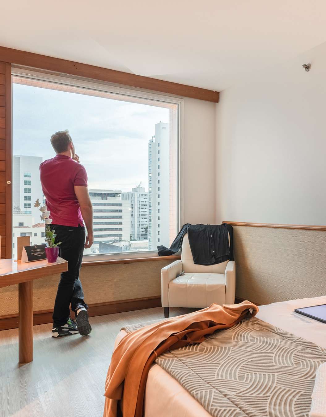 Man admiring the view from the window of a hotel room at Pestana São Paulo, a hotel in downtown São Paulo