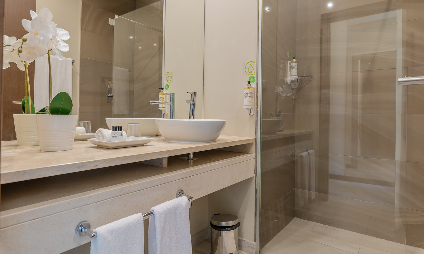 The Garden Suite at Pestana Alvor Park has a bathroom with a bathtub and a sink with a flower vase