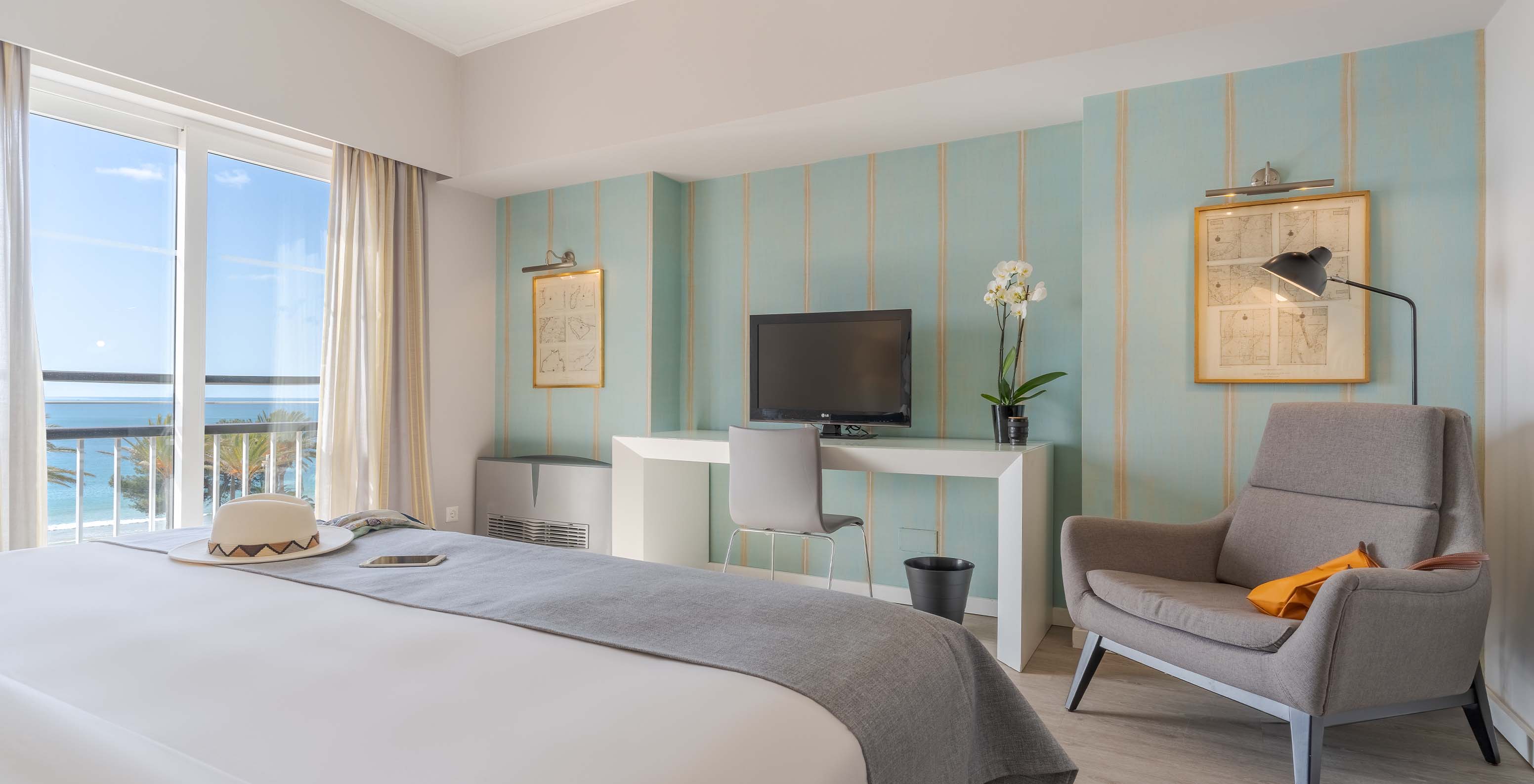 The Luxury Sea View Suite at Pestana Alvor Praia has a double bed, an armchair, a desk with TV, and sea views