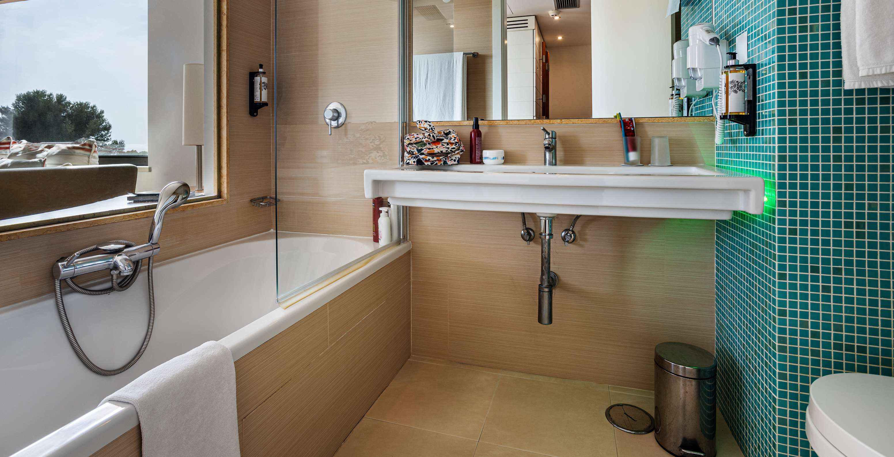 The Deluxe Lateral Sea View room at Pestana Dom João II features a bathroom with a sink, mirror, and bathtub