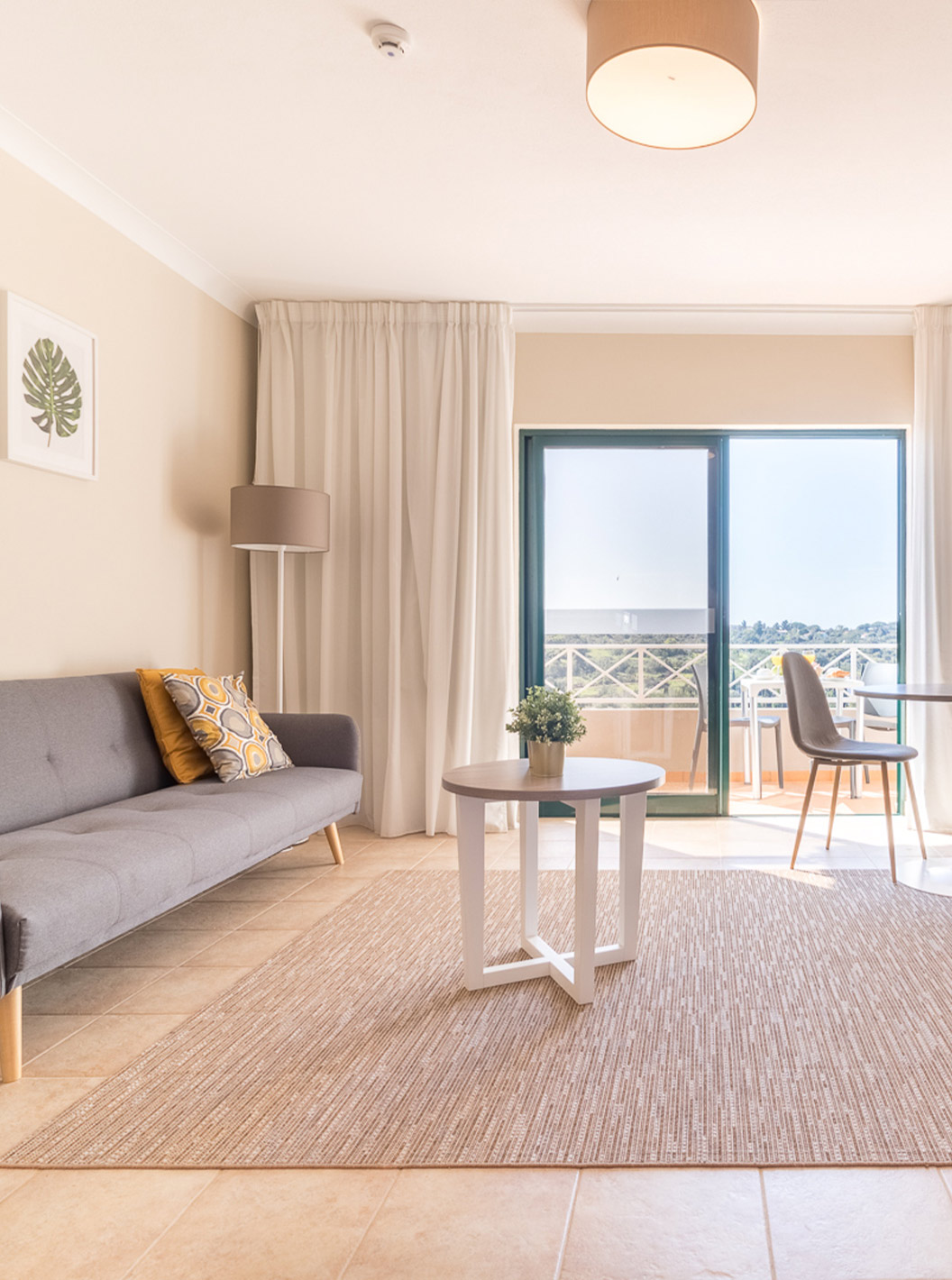 The studio at Pestana Gramacho Residences has a living room with gray sofa, TV, coffee table and bright balcony