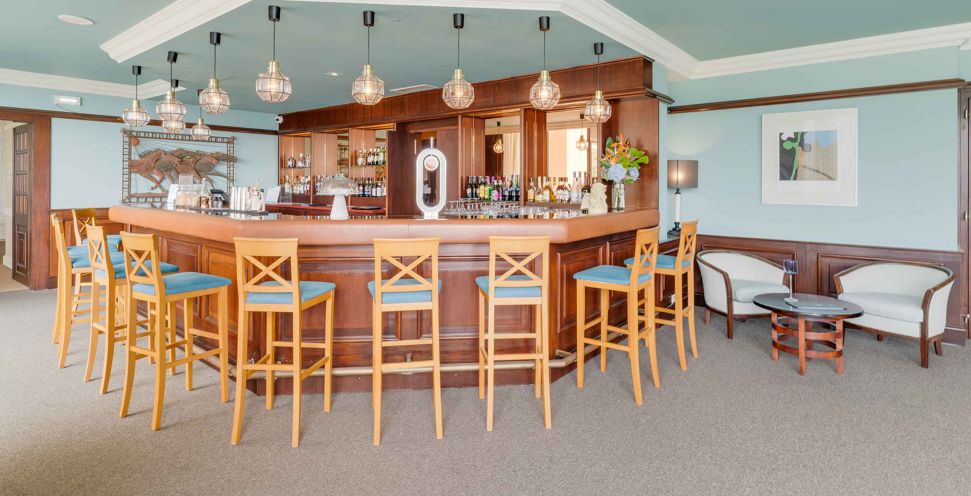 Bar at Pestana Bahia Praia with high chairs, wooden counter, and modern lighting with hanging bulbs