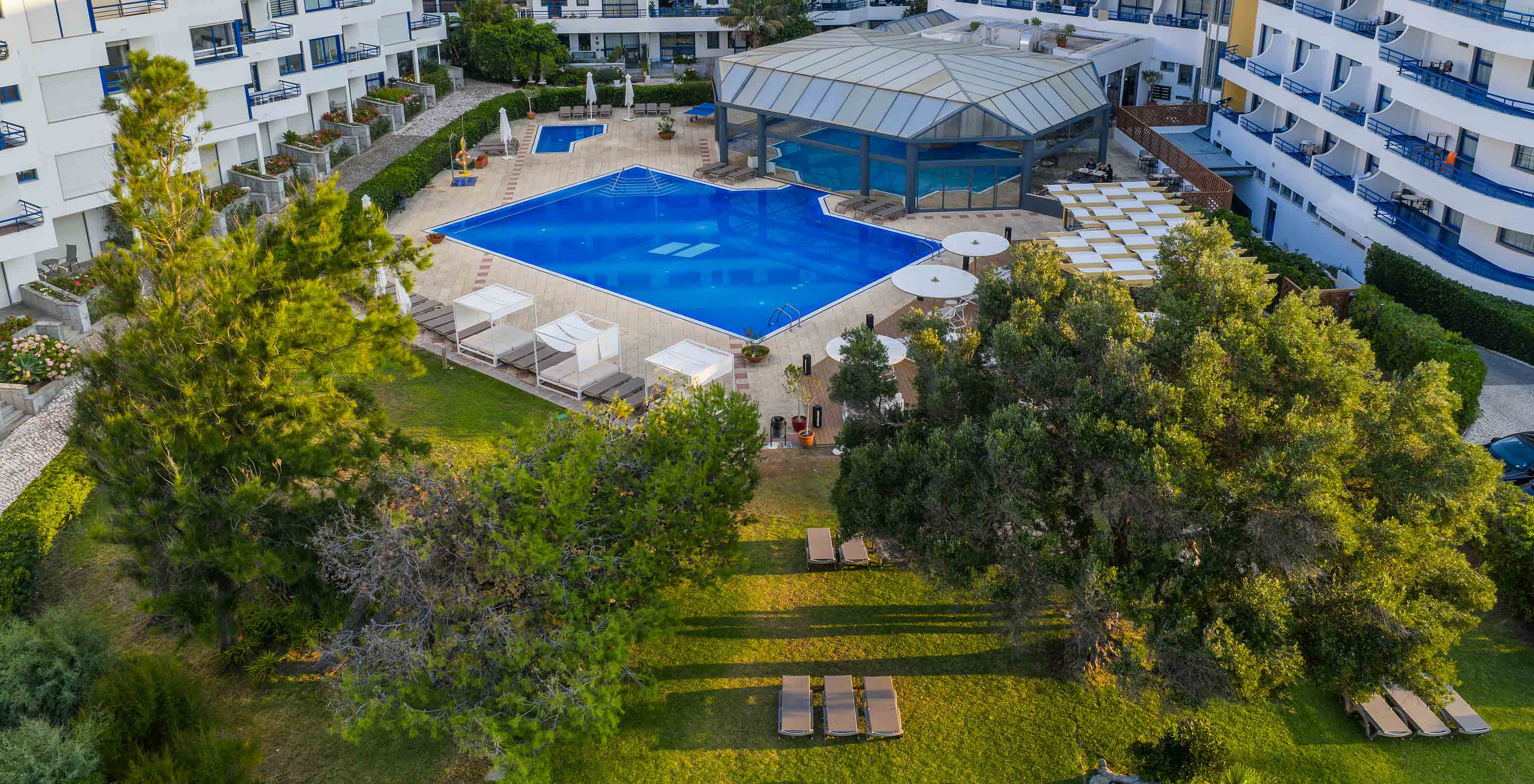 Pestana Cascais garden with outdoor pools for adults and children, indoor pool, and some sun loungers