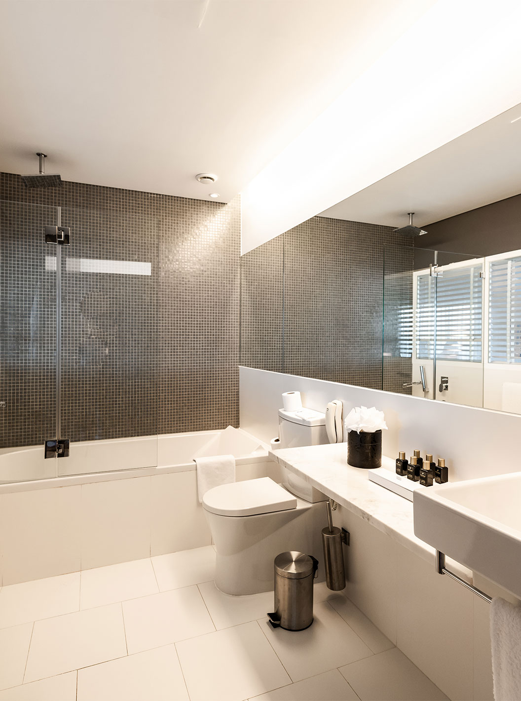 The Suite at Pestana Cidadela Cascais has a large bathroom with a sink with a mirror, toilet, and a bathtub with a shower