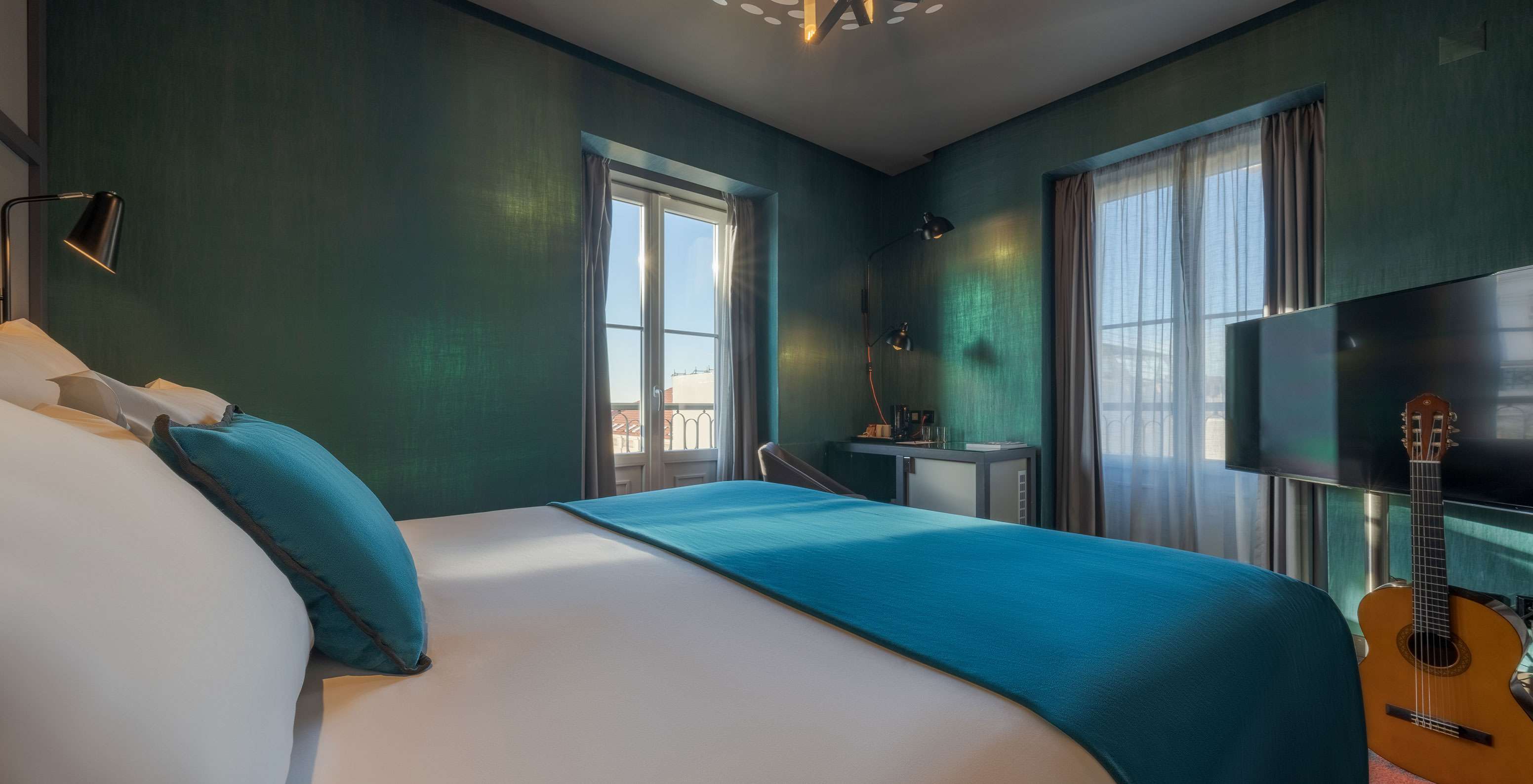 The CR7 Superior Corner Room at Pestana CR7 Lisboa features a bed and two windows overlooking Lisbon's Historic Center