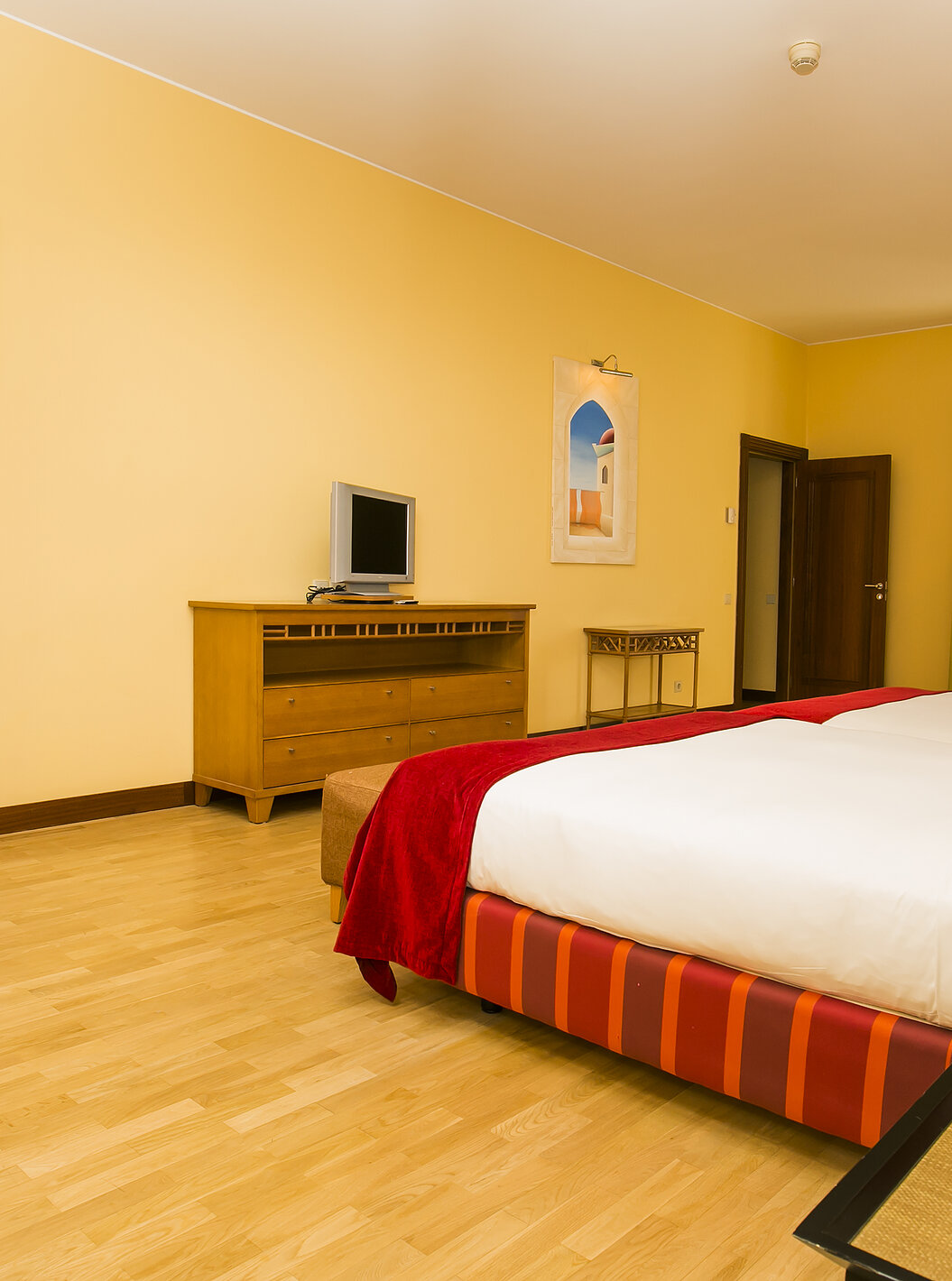 The Deluxe Mezzanine Suite of Pestana Sintra Golf has two beds, a small television, and a window with balcony access