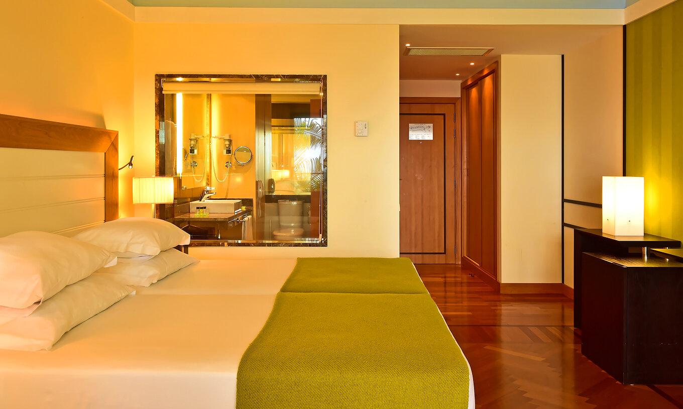 The Classic Sea View of Pestana Promenade has a bed with a green bedspread and a glass to the bathroom at the back