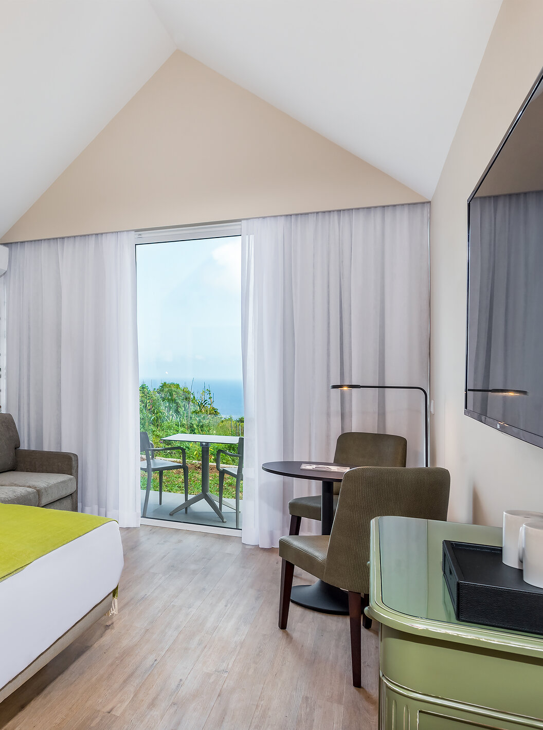 The Garden View Studio of Pestana Quinta do Arco has a double bed, sofa, side table, television, and balcony with sea view