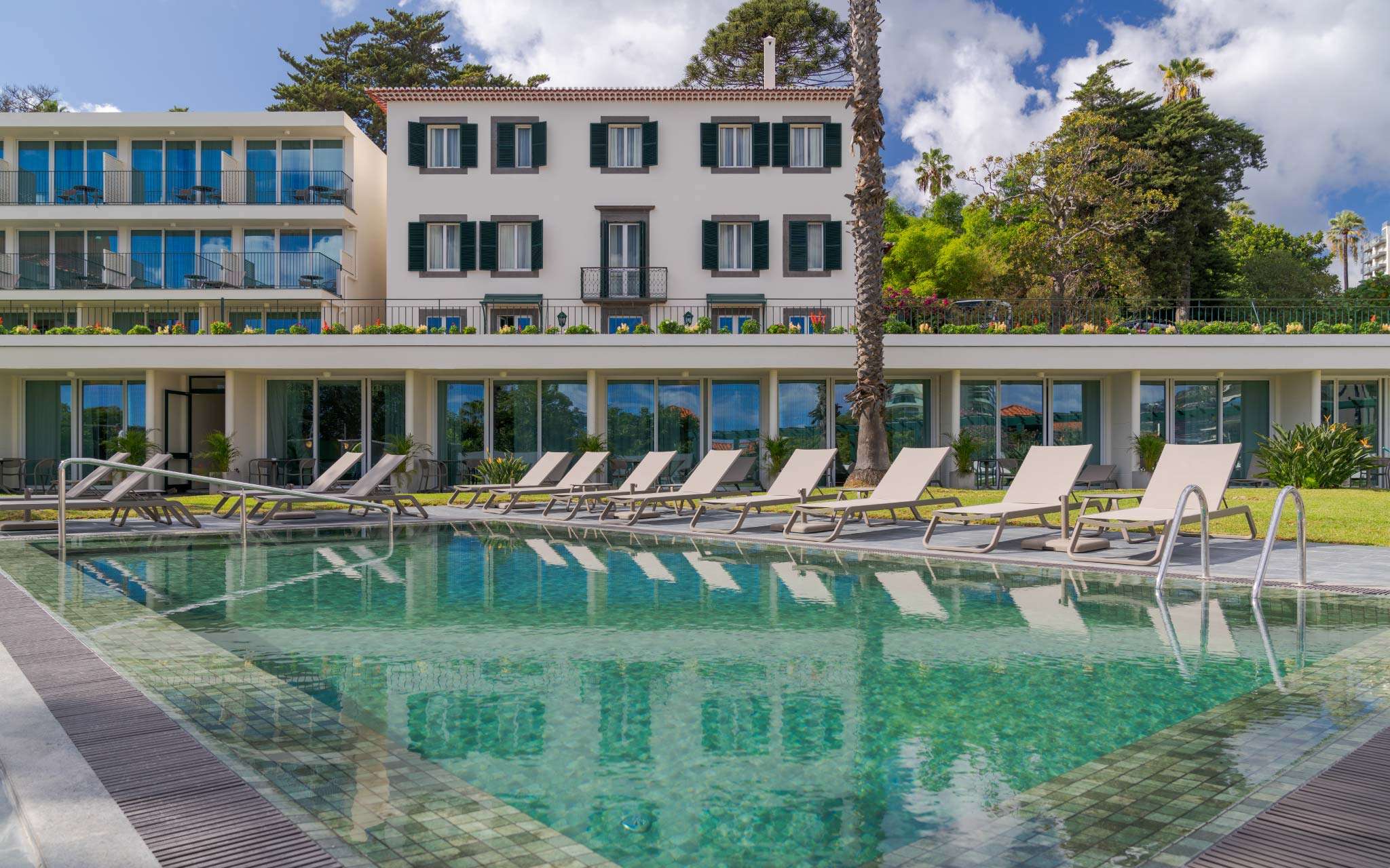 View of the outdoor pool at Pestana Quinta Perestrello, a Charming Hotel in Madeira, with the building behind