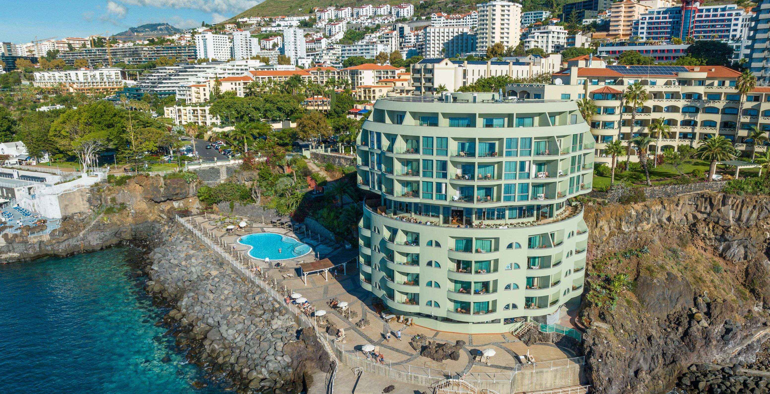 View of Pestana Vila Lido Madeira, a building with an outdoor pool, sunbeds, and direct access to the sea