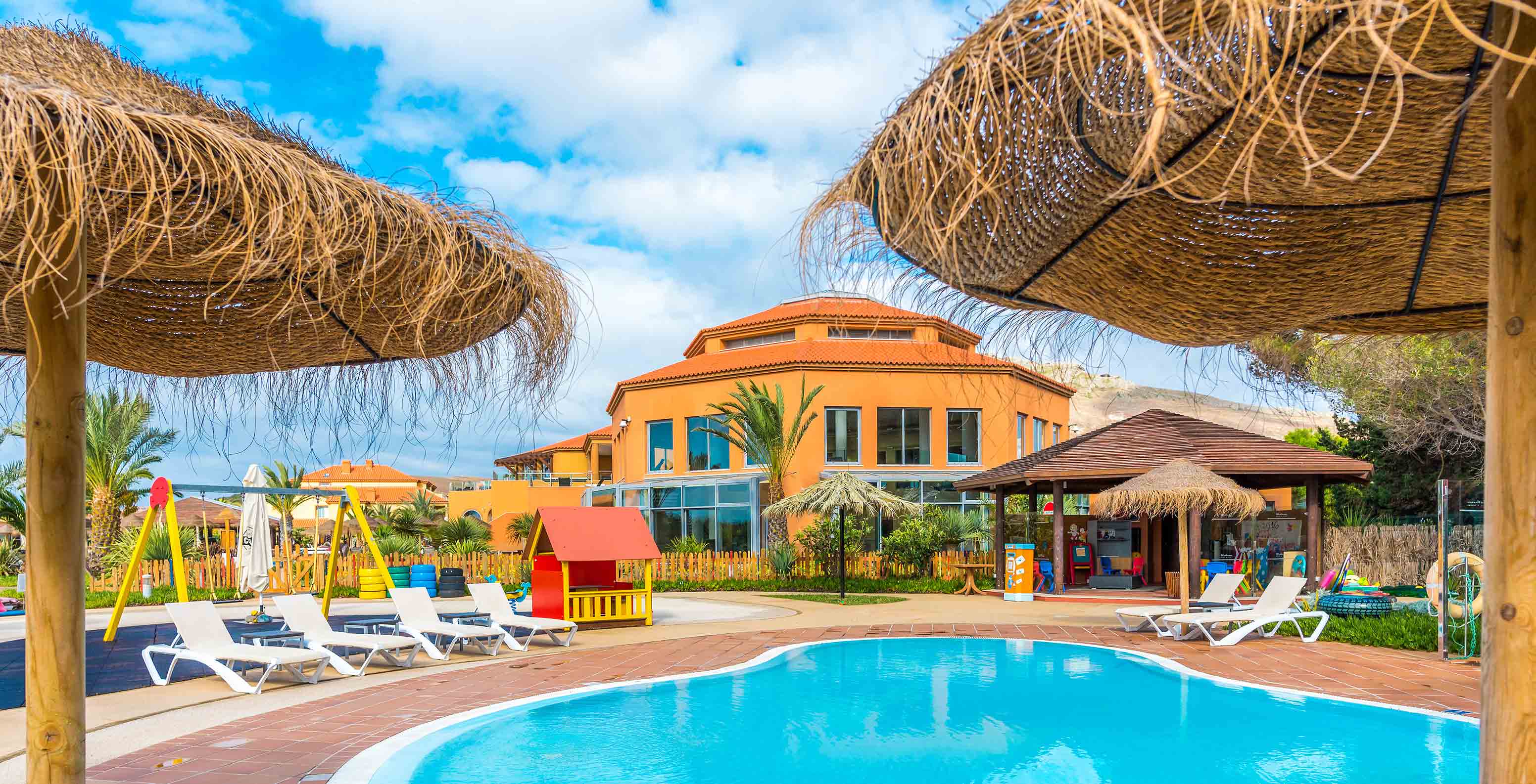 Kids' pool & playground at Pestana Porto Santo, straw parasols, building backdrop