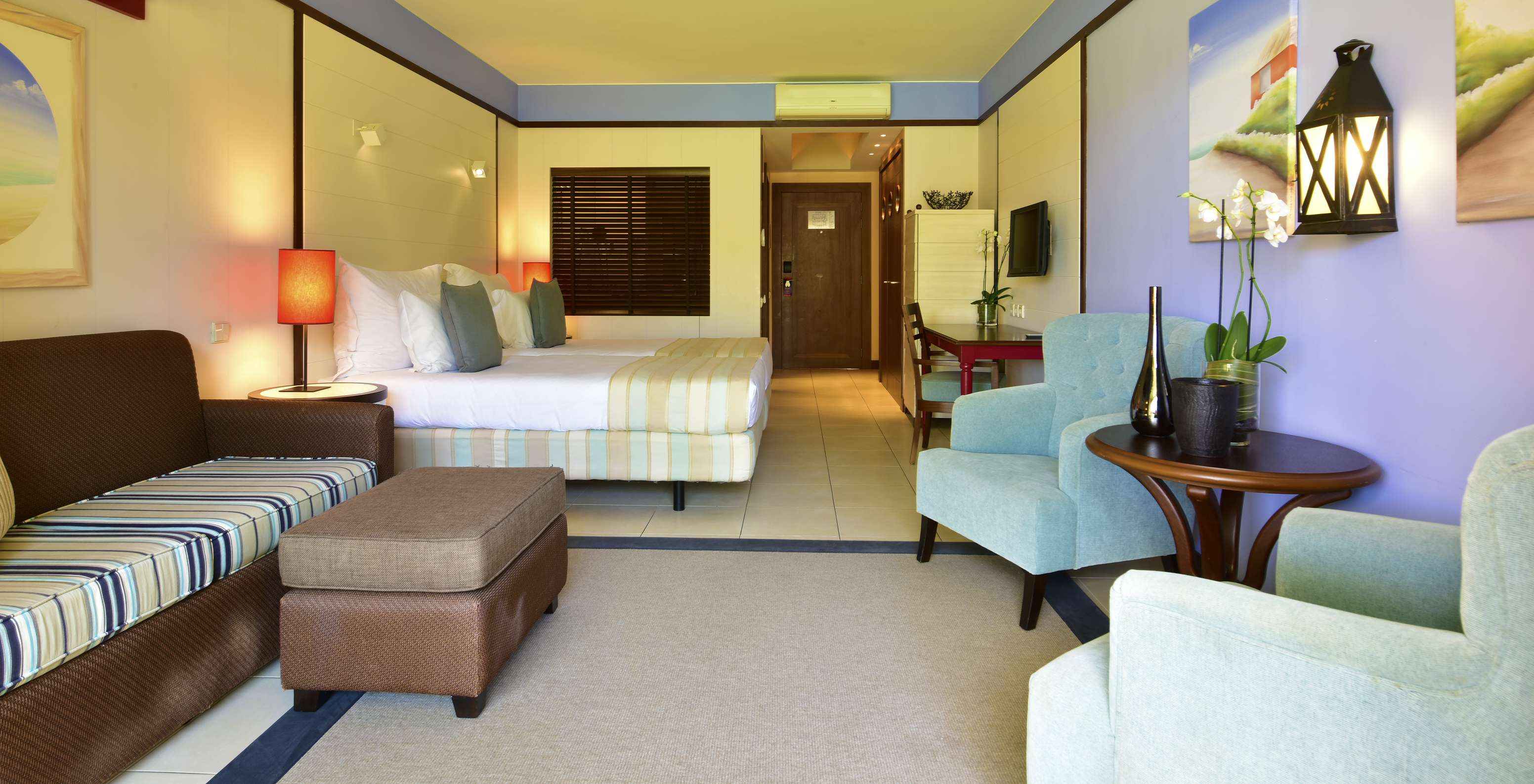 The Pool View Double of Pestana Porto Santo All Inclusive has a sofa, two armchairs, two beds, a television, and a desk