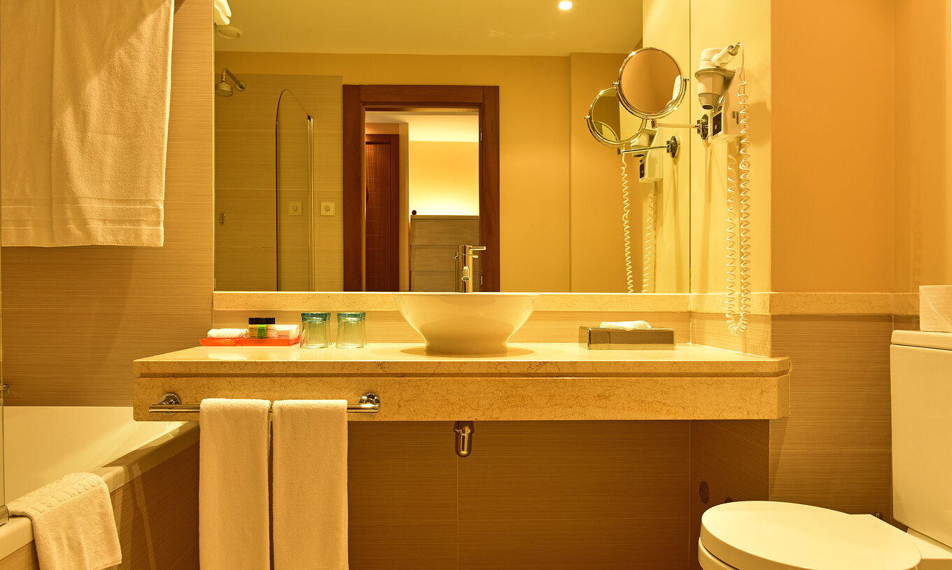 The Classic Double of Pestana Porto Santo All Inclusive has a bathroom with sink, mirror, toilet, and towels