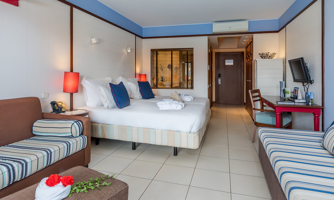 The Family Double of Pestana Porto Santo All Inclusive has two beds, two sofas, a desk, and a television