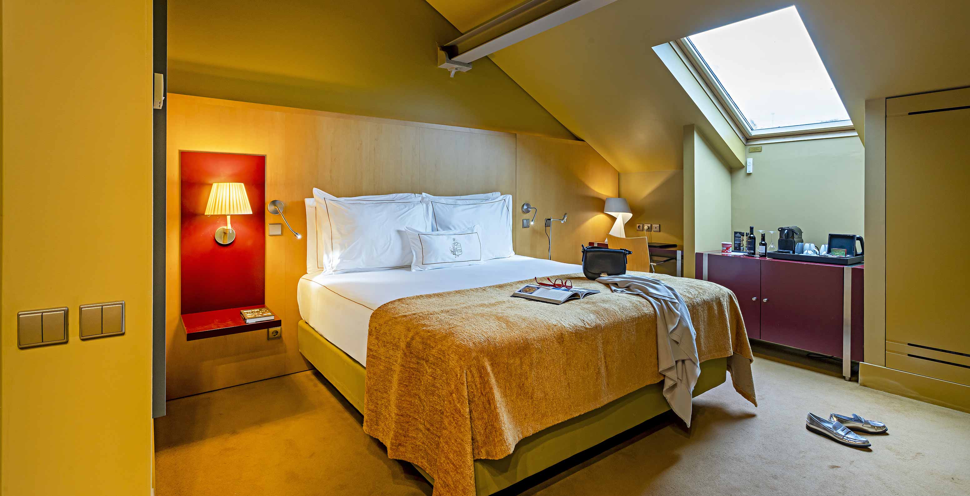 Pestana Palácio do Freixo’s Classic Attic has a bed with a yellow cover and a red bedside table