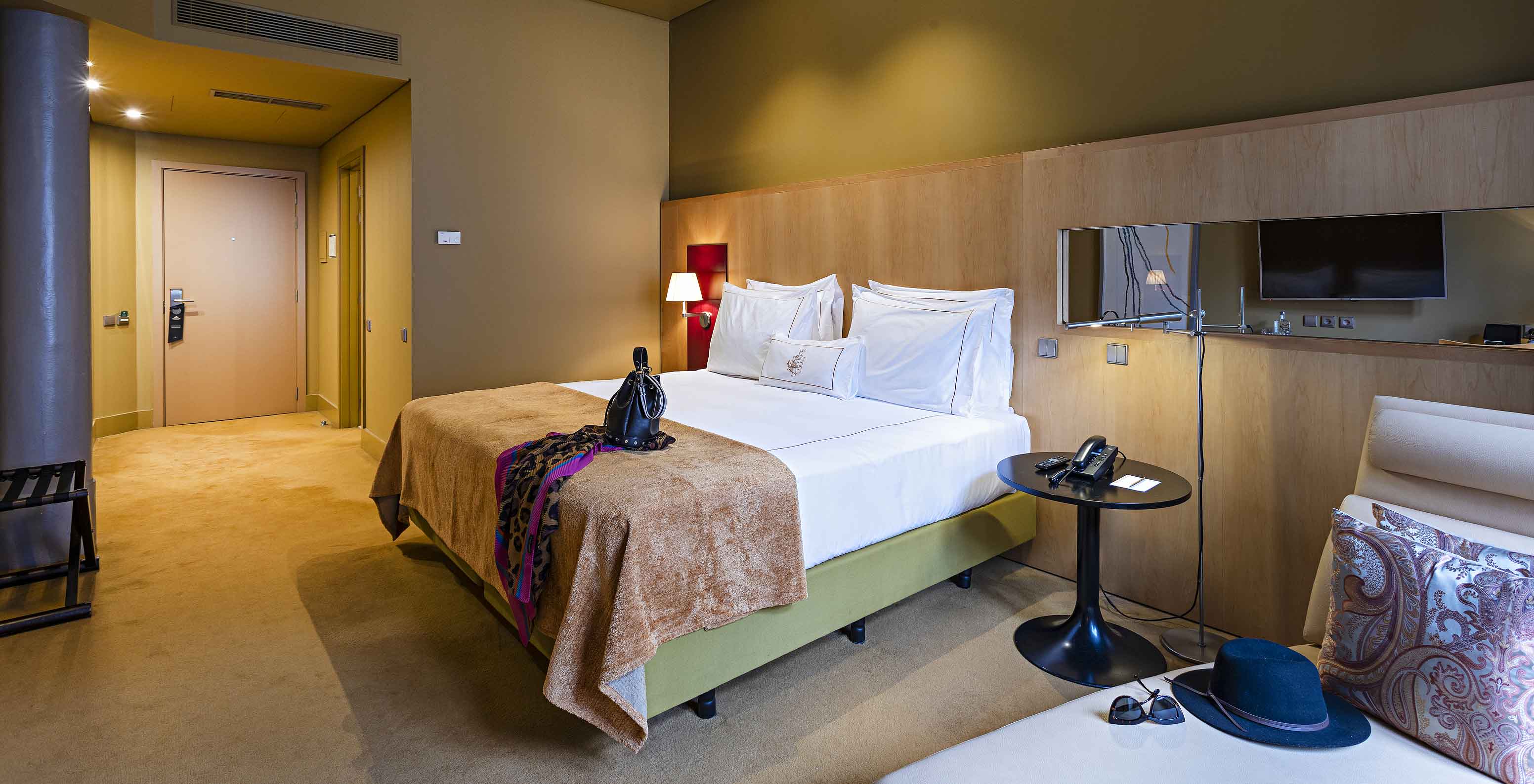 Pestana Palácio do Freixo’s Classic room has yellow walls, a double bed, and a beige sofa bed