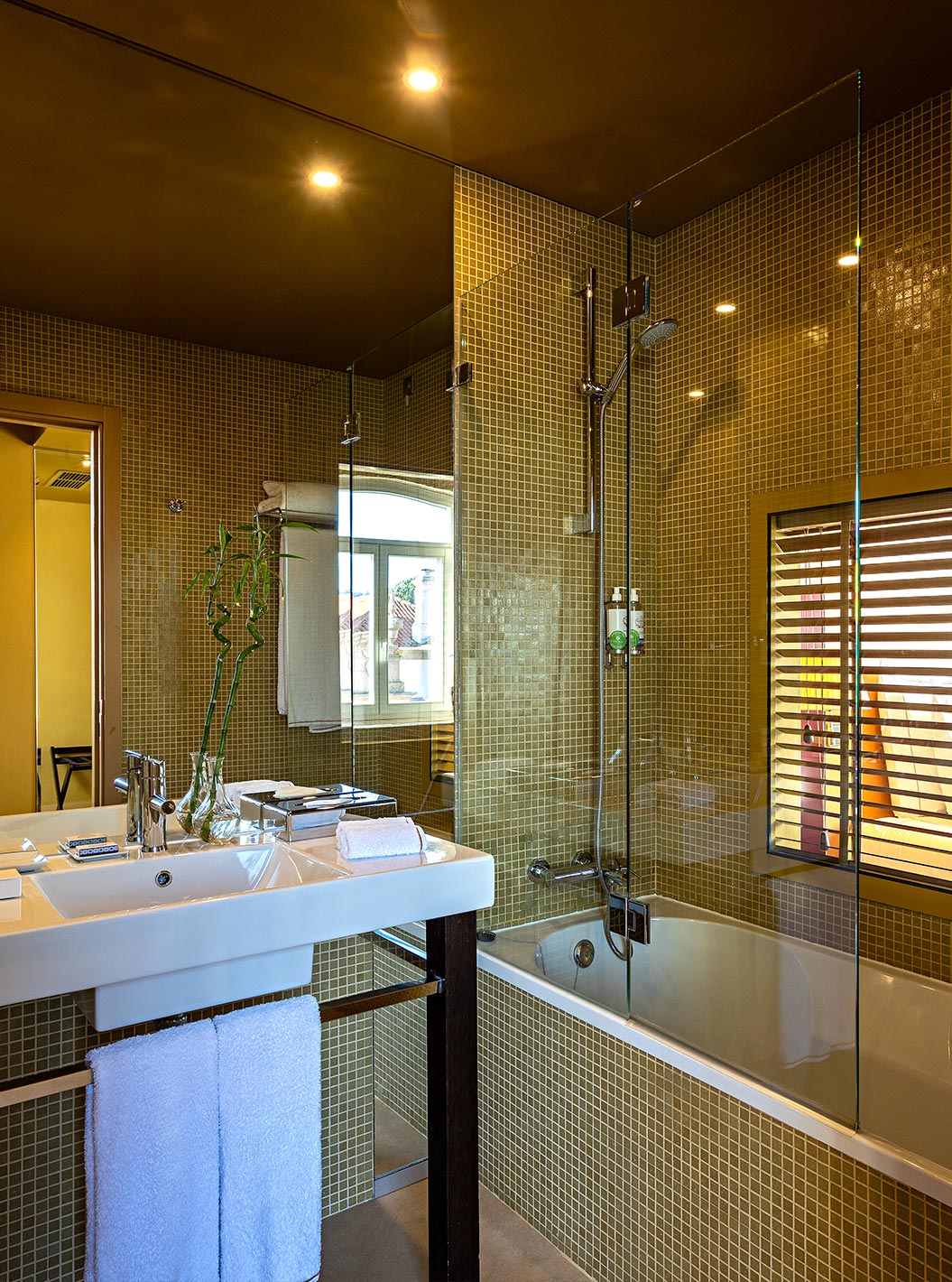 The Deluxe Grand View has a bathroom with a bathtub and a window to the bedroom