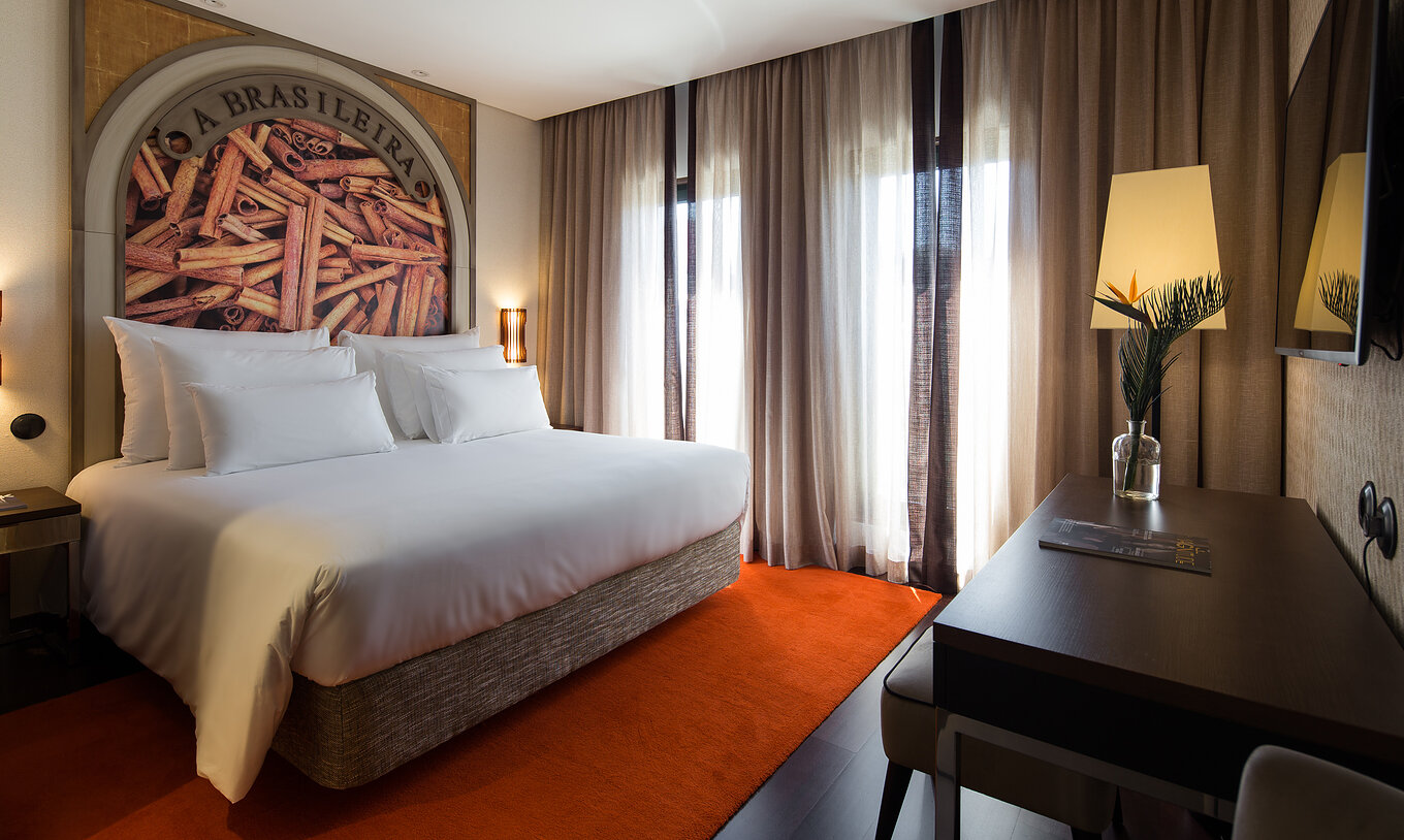 The Deluxe Executive Grand View do Pestana Porto - A Brasileira has a king size bed with a themed mural about cinnamon