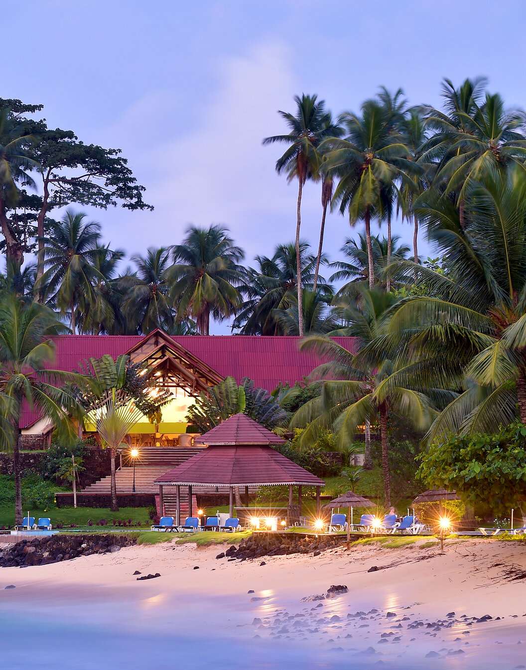 Beach and building with sun loungers and palm trees of Pestana Equador, a hotel on Ilhéu das Rolas, São Tomé