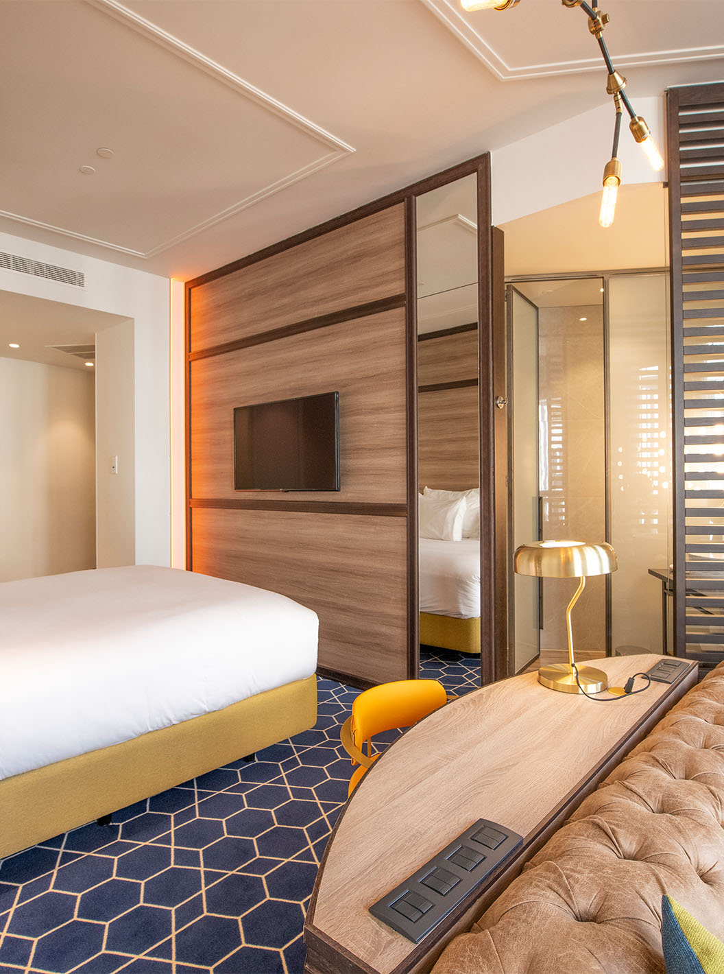 The Fantastic 7 Room at Pestana CR7 Gran Vía Madrid includes a double bed, sofa, desk, mirror, and wooden partition