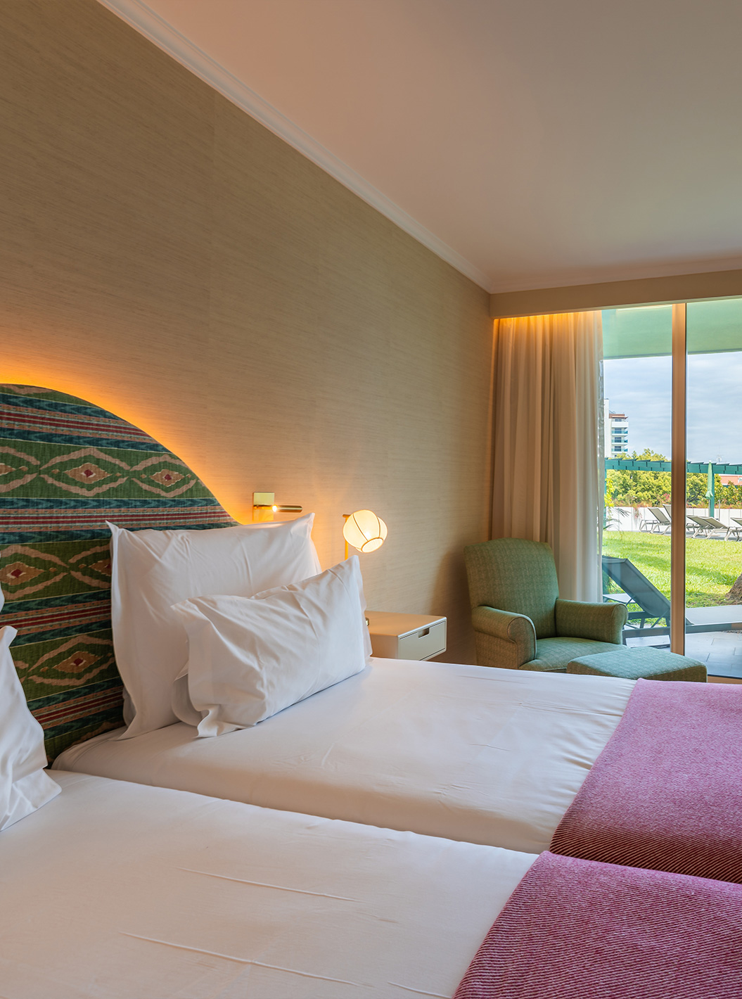 The Pool View Room at Pestana Quinta Perestrello has a double bed, an armchair, and a balcony overlooking the garden.