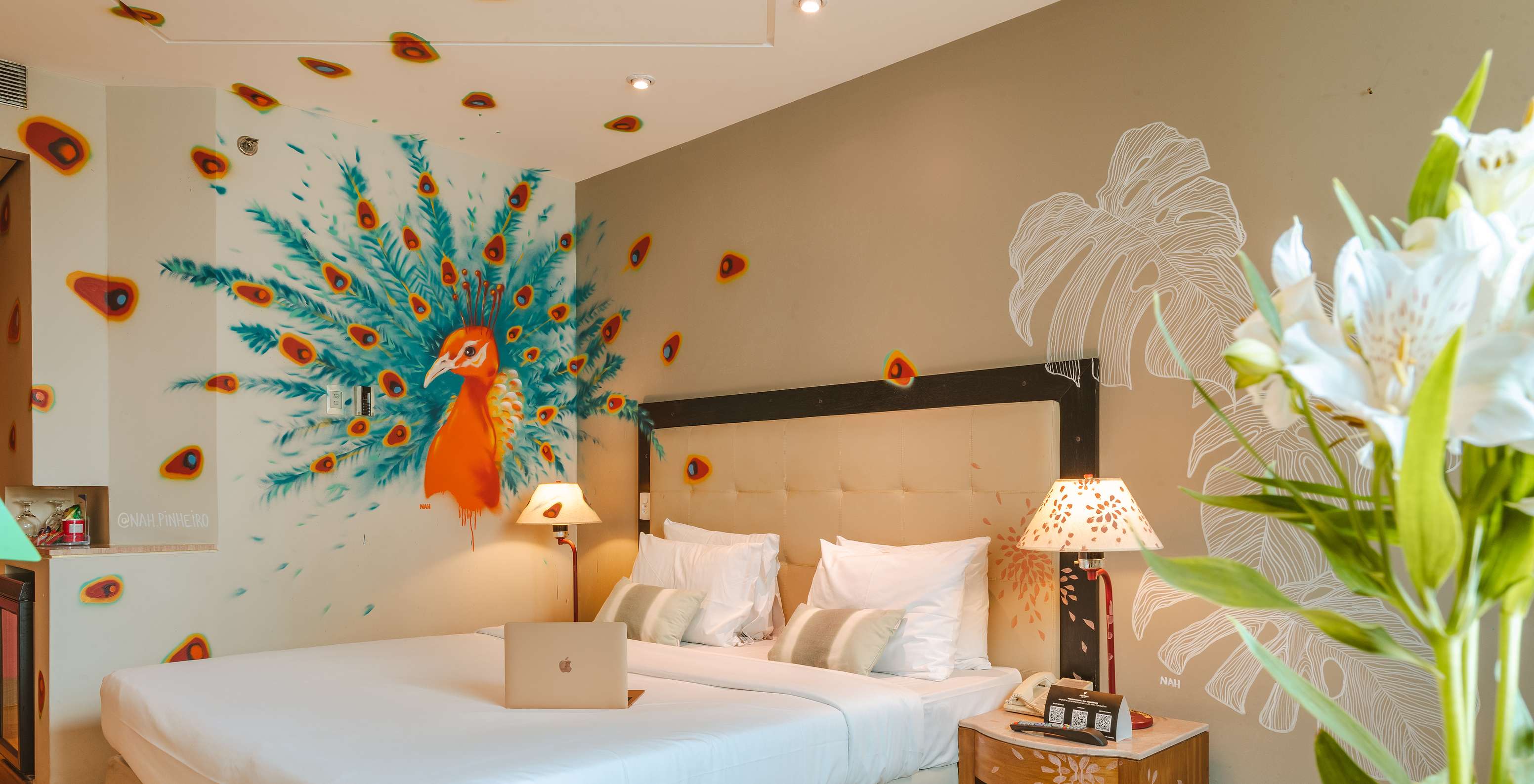 Habitación decorada por la artista Nah Pinheiro con un pavo real colorido en la pared en hotel 4 estrellas en São Paulo