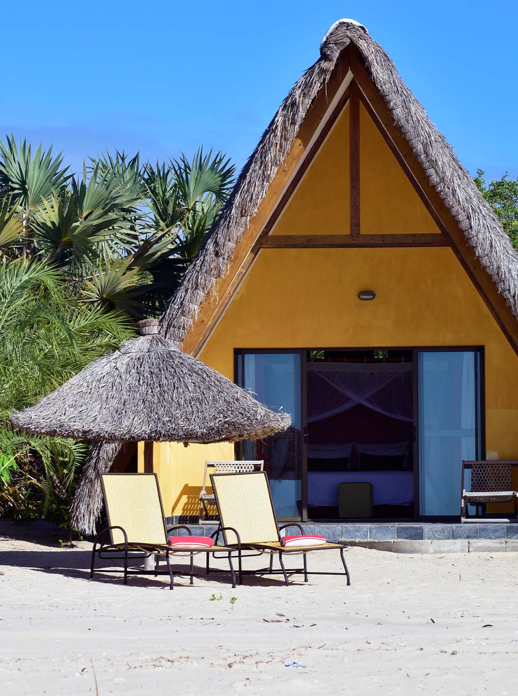 El Bungalow T1 del Pestana Bazaruto Lodge es una casita amarilla en la playa con techo de paja en forma de A