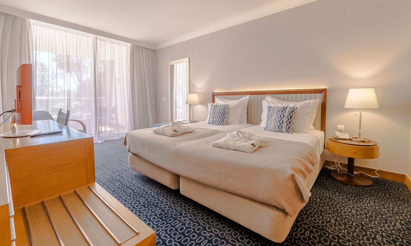 El T1 - 1 Habitación del Pestana Alvor Park tiene una cama de matrimonio, moqueta azul y un escritorio televisión