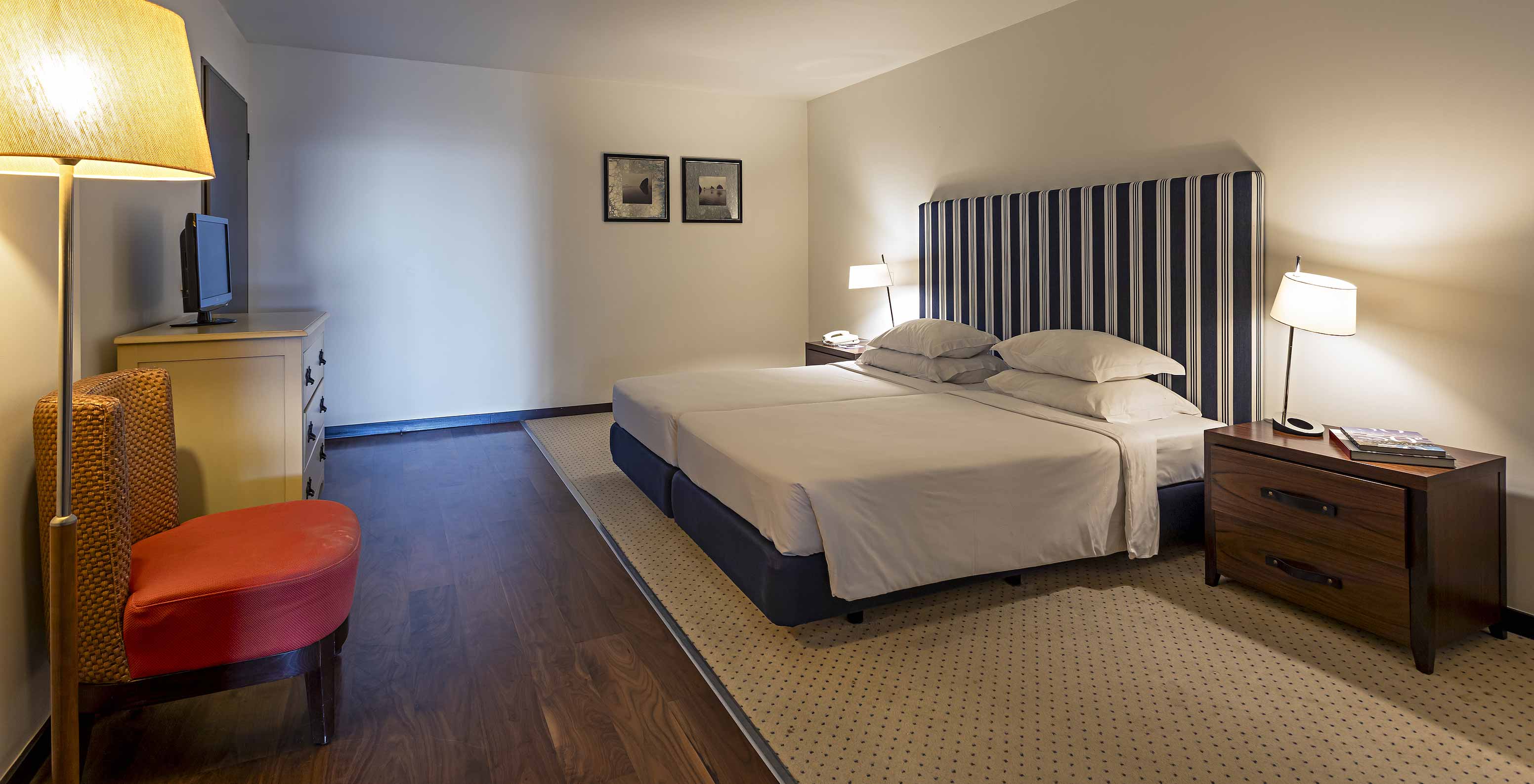 La Cliff Suite T2 en Pestana Alvor Praia tiene un dormitorio con una cama doble, dos cuadros y una cómoda con televisión