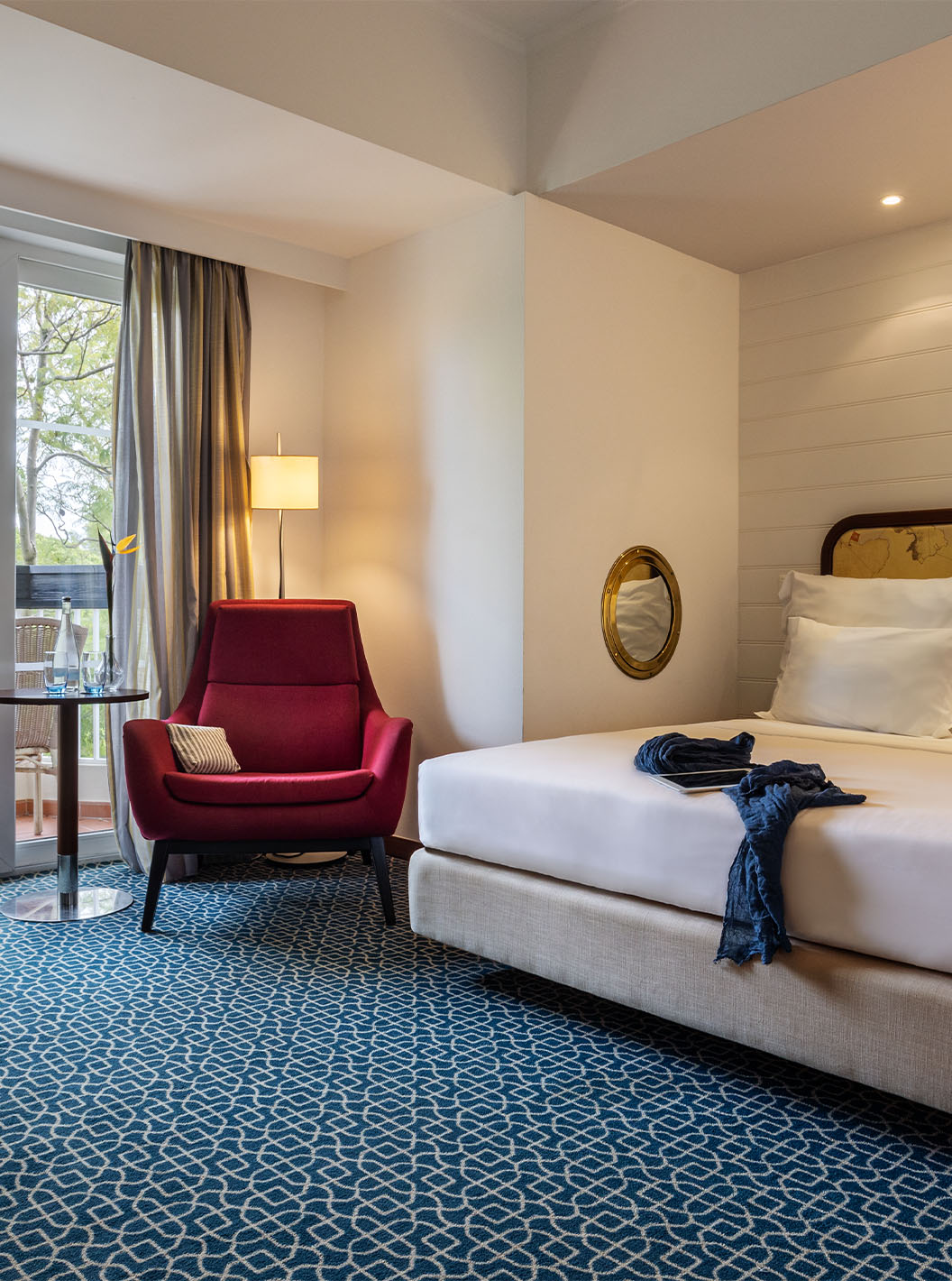 La Suite Vista Jardín del Pestana Alvor Praia tiene cama matrimonial, sillón rojo y terraza con vista jardín y sillas