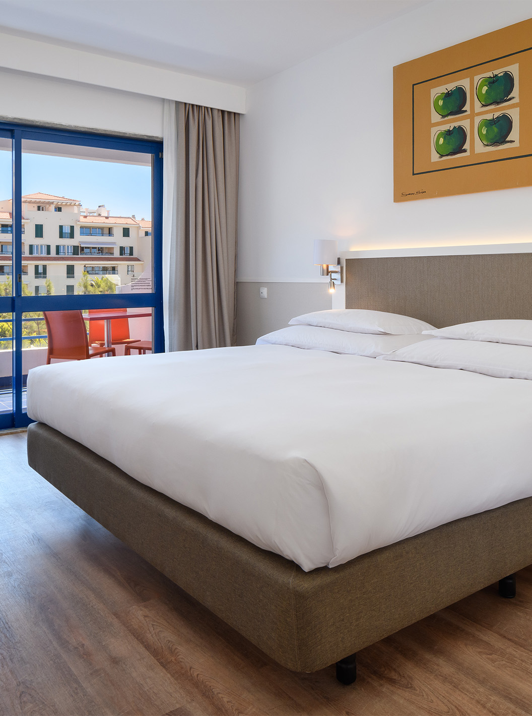 La Suite Deluxe del Pestana Cascais cuenta con cama de matrimonio, escritorio y un cuadro pintado en la pared