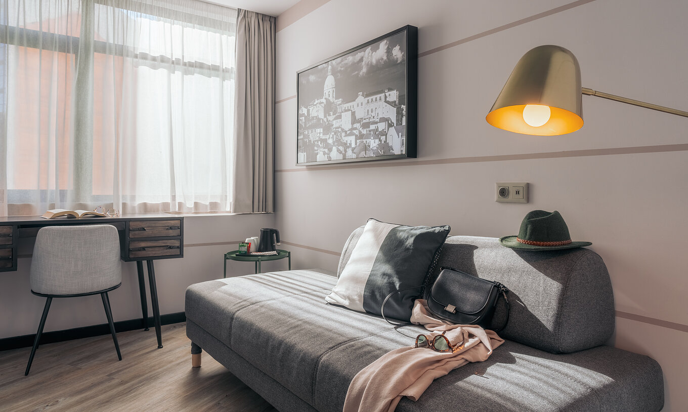 El Double Superior del Pestana Lisboa Vintage tiene un sofá gris, un escritorio con silla, una mesa auxiliar y un cuadro