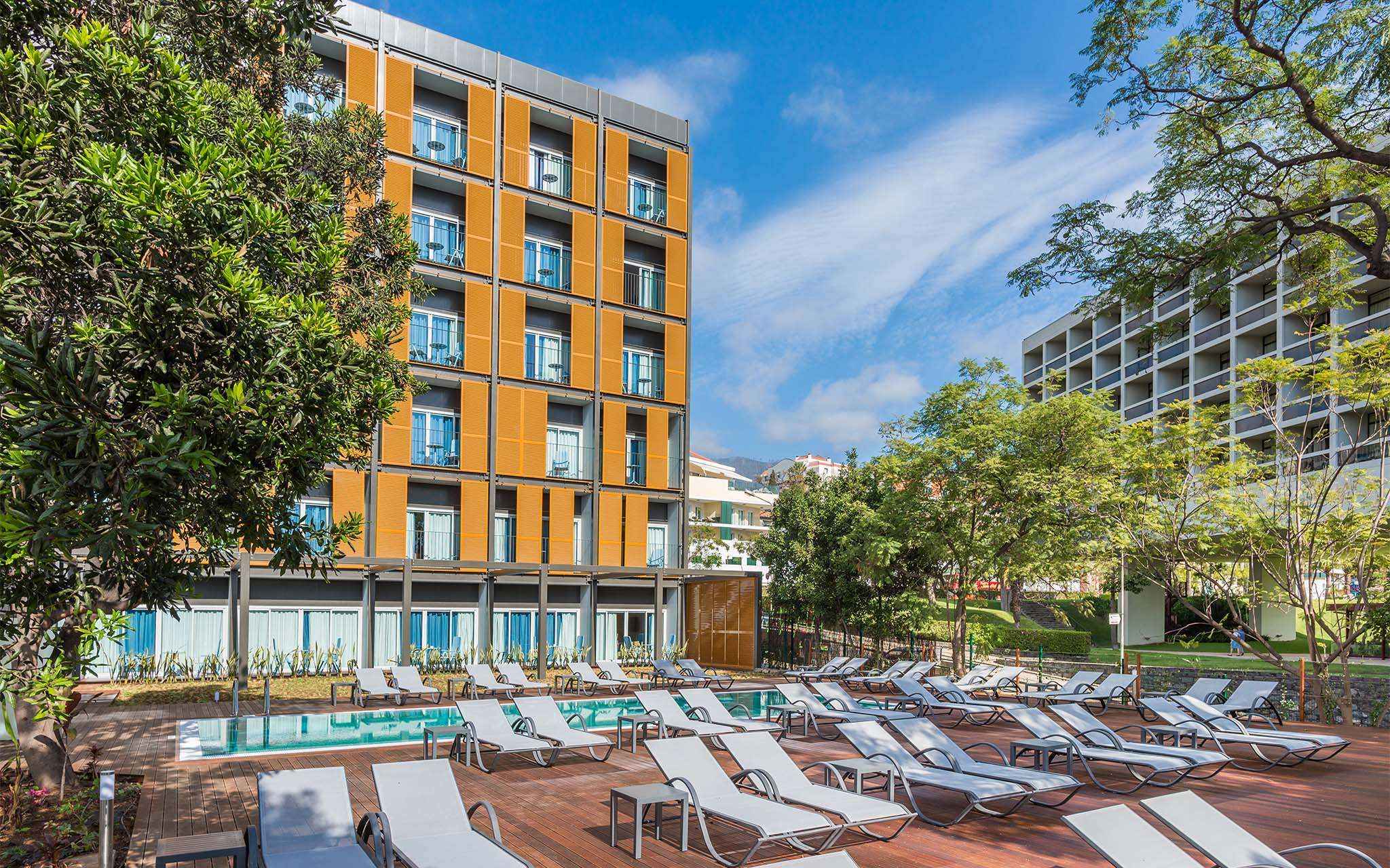 Vista exterior de Pestana Casino Studios, con apartamentos en el centro, piscina y un edificio naranja