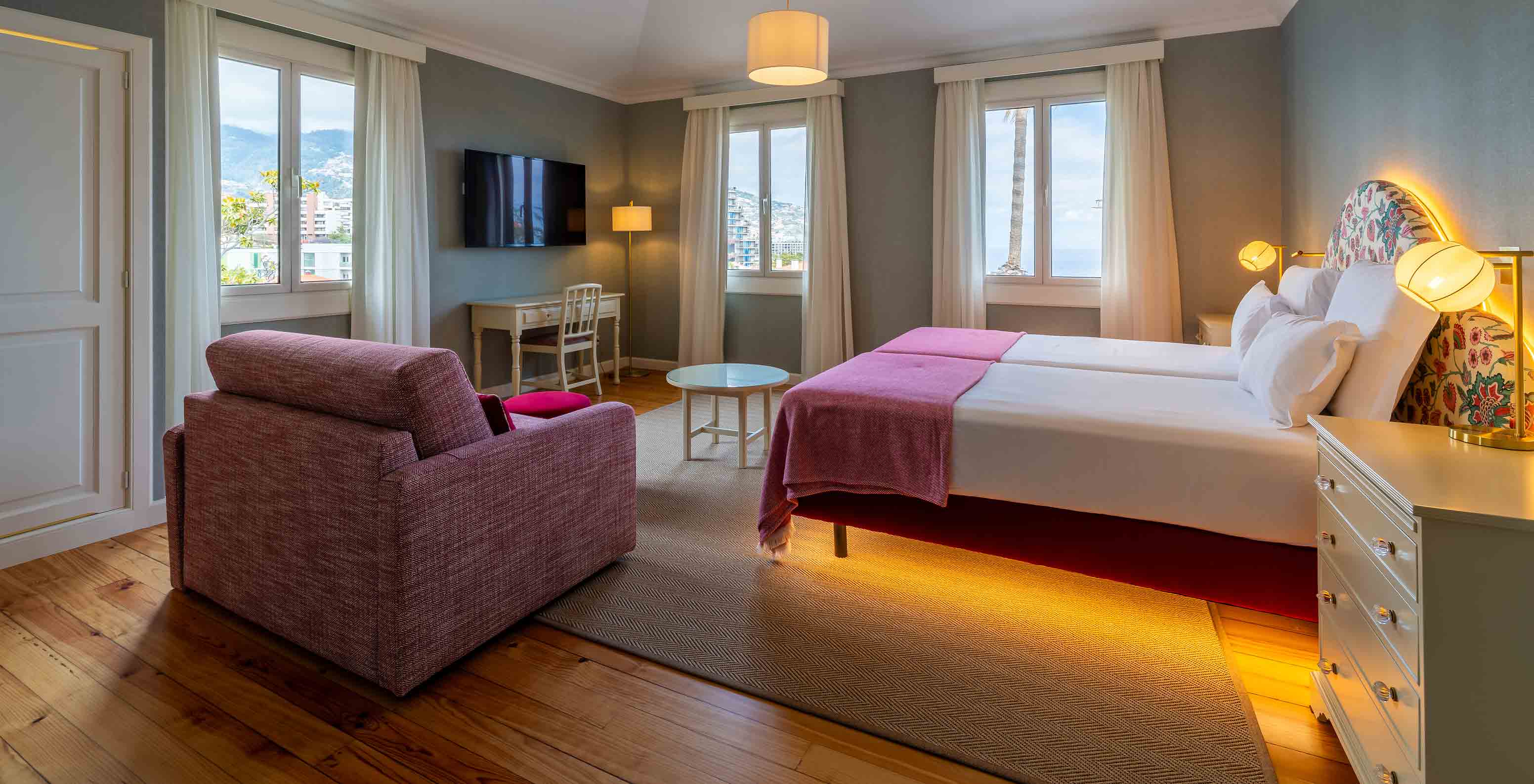 La Junior Suite Vista Mar Parcial del Pestana Quinta Perestrello tiene una cama doble, un sofá y televisión.