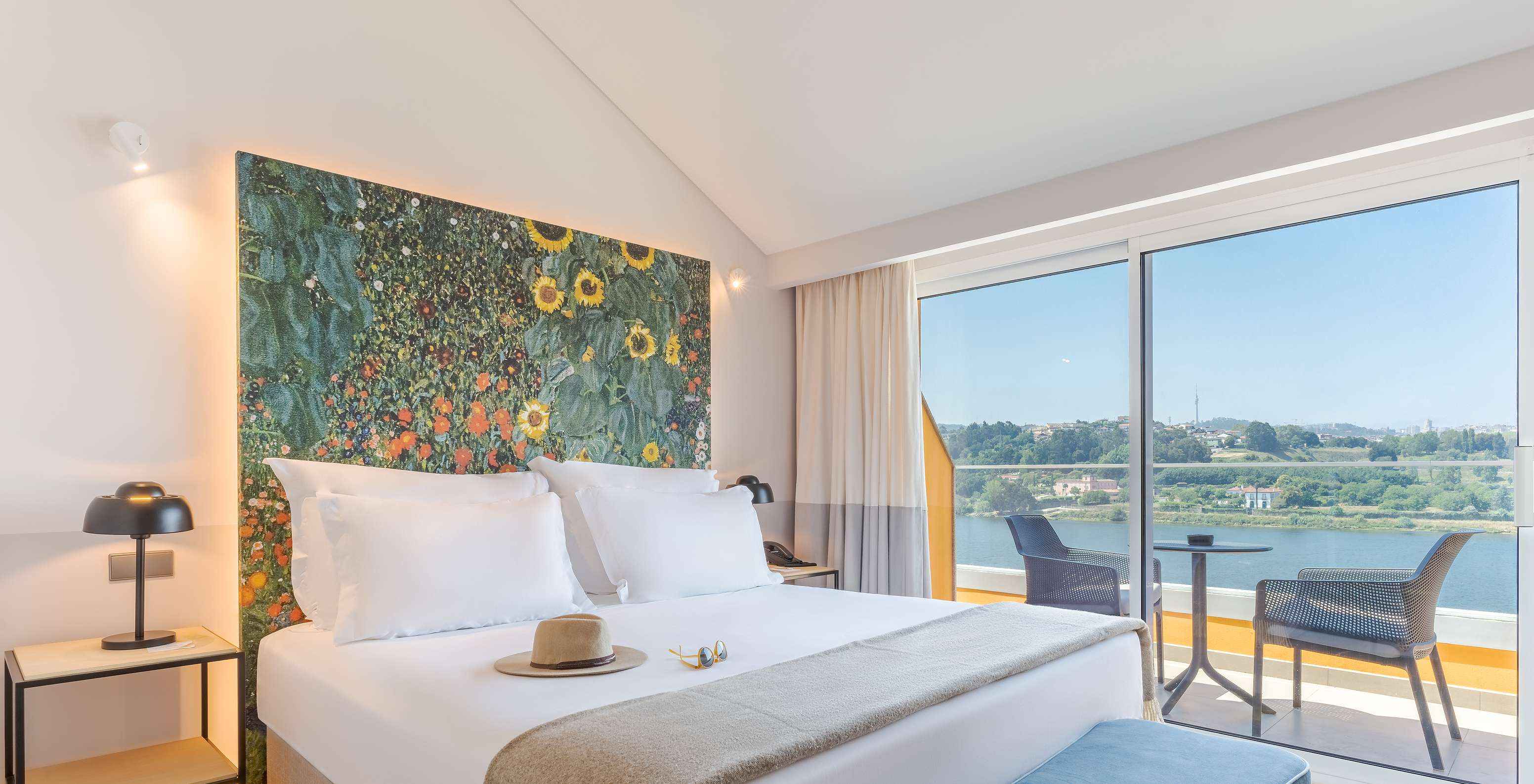 La Junior Suite del Pestana Douro Riverside cuenta con una cama de matrimonio, mesa de noche con lámpara y terraza con vista