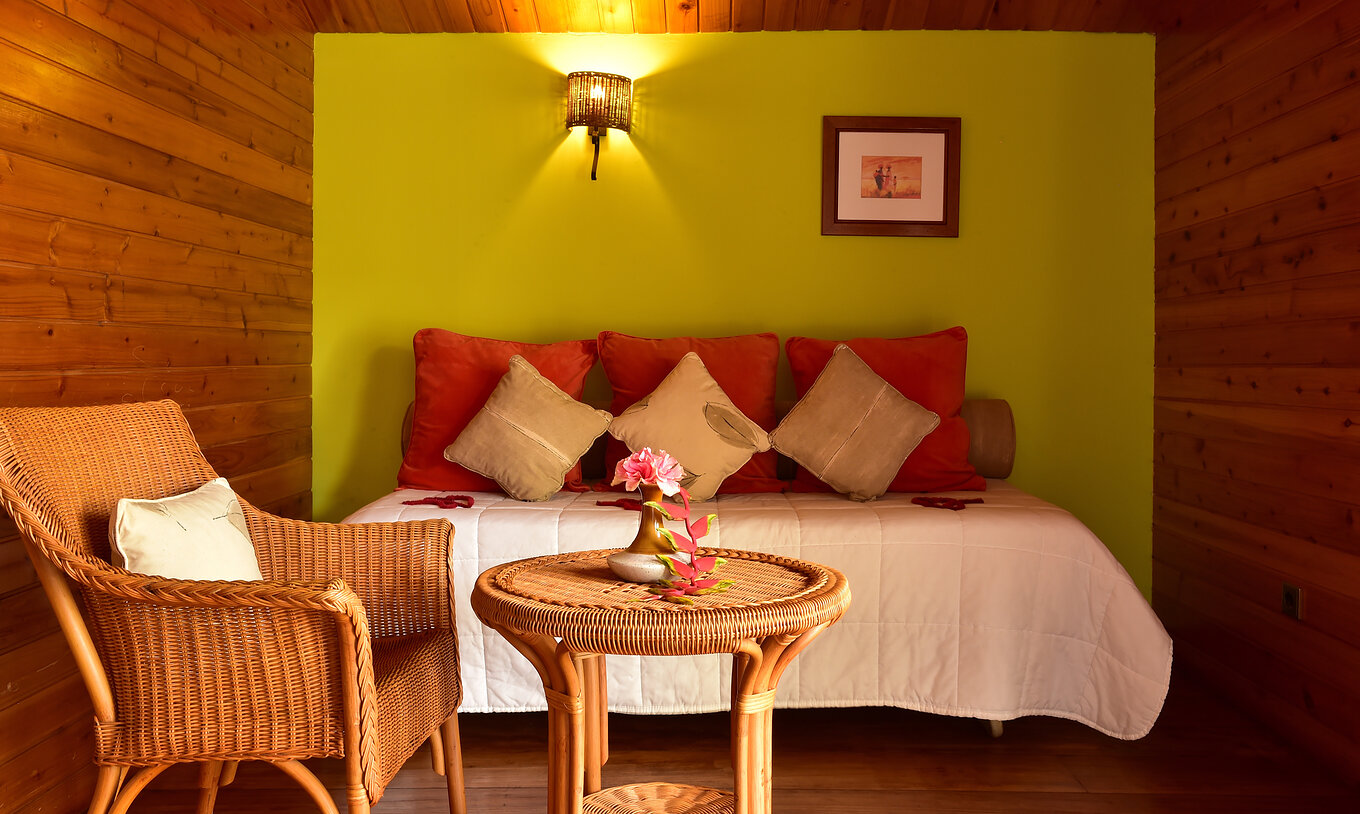 La Standard Suite del Pestana Equador Ilheu das Rolas tiene una pared verde, una cama, una mesa y una silla de mimbre