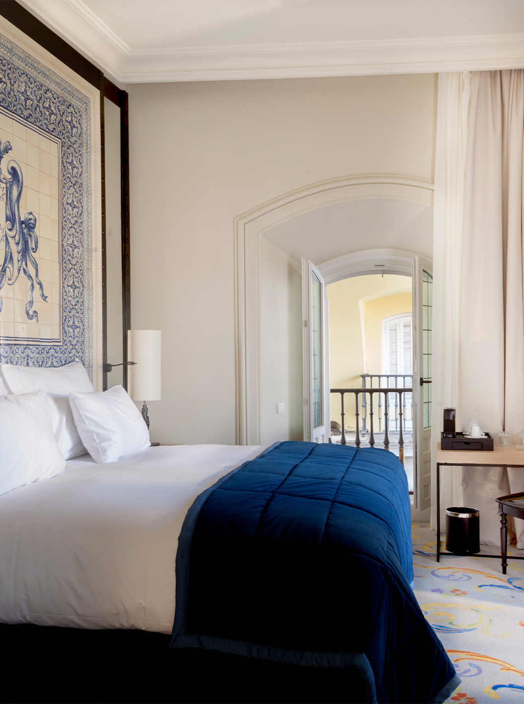 La Suite Plaza Mayor del Pestana Plaza Mayor Madrid tiene una cama de casal y una cabecera con azulejos azules y blancos