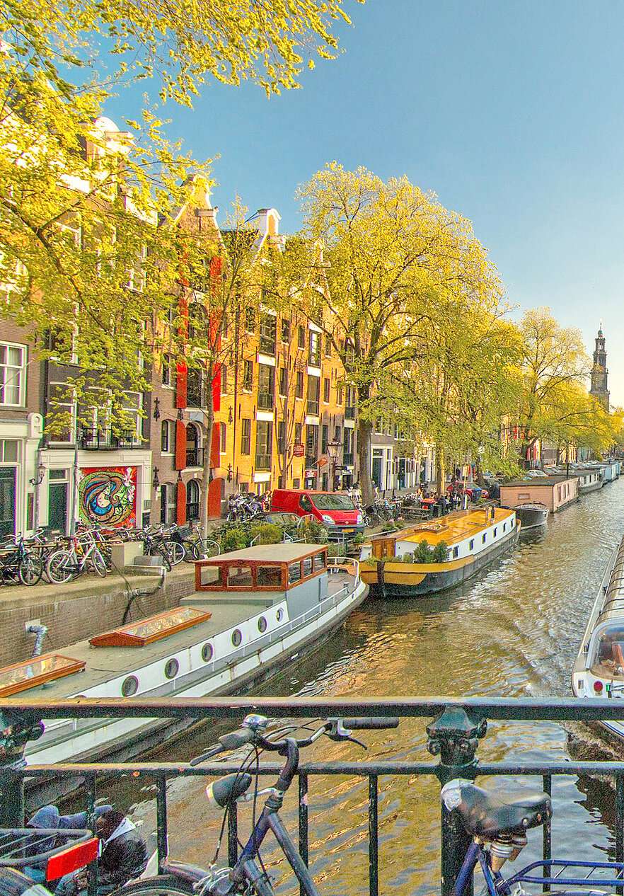 Descubra los Países Bajos y explore la belleza de los canales de Ámsterdam y sus impresionantes edificios típicos.