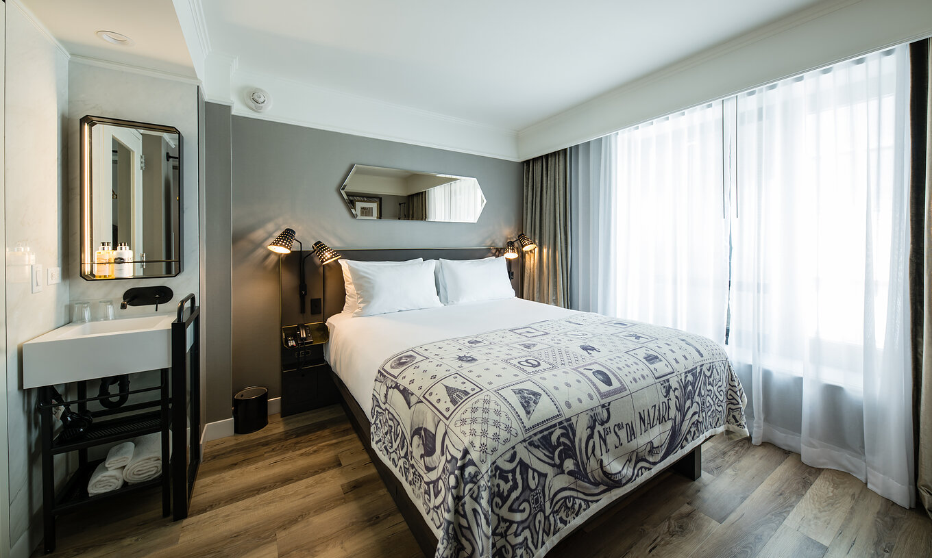 La habitación Superior del Pestana Park Avenue cuenta con una cama, lavabo y espejo en la habitación, y mesa de noche